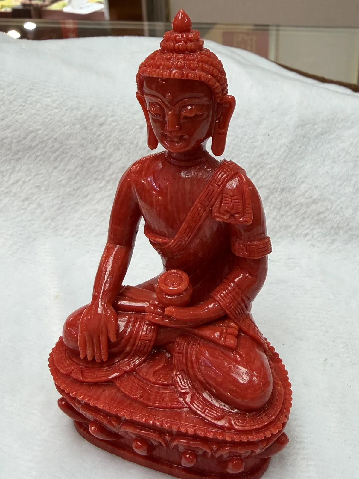 【红珊瑚释迦牟尼佛中号佛像摆件】佛祖庄严肃穆，佛像顶结高肉螺髻，髻顶可见顶严，双耳垂肩，脸型清秀，双眉高挑，高鼻细挺，身着袒右式袈裟，左手持钵，裸双足结跏趺坐于莲台之上，莲台高起，饰有饱满的连珠纹，底部有开孔，可藏经文珠宝等，材料为天然意大利沙丁，台湾拼接工艺，做工精良，裸石尺寸110*63.7*43.6mm，重量120.25克。