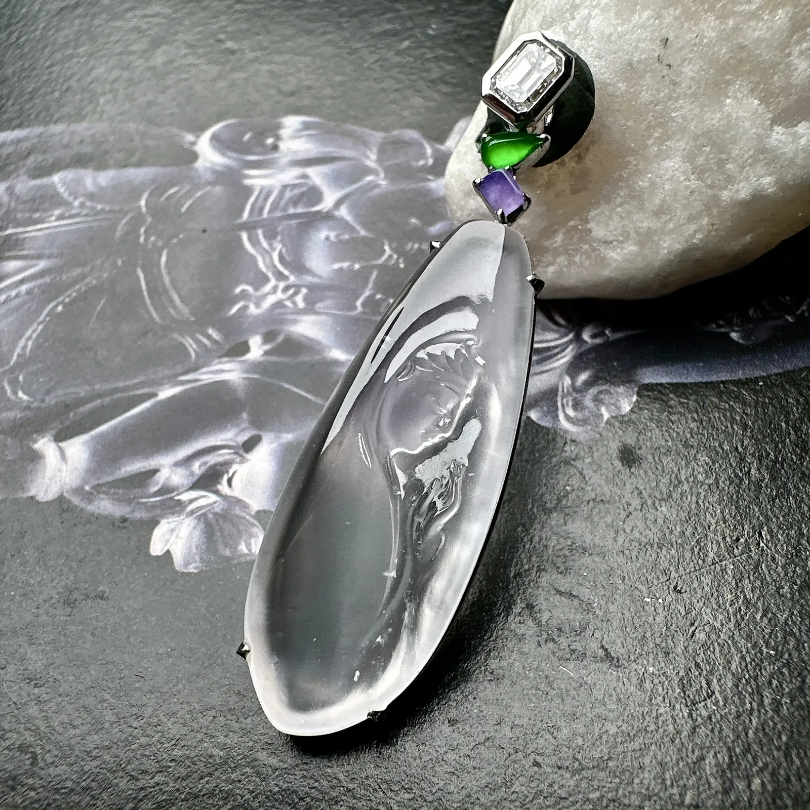 【玻璃种观音首吊坠】侧面像，料子通透闪亮，质地致密，种老起强胶感，玻璃光泽强烈。人物面部开脸生动，雕刻很精细，表情端庄祥和。料子纯净，18K金钻镶嵌，裸石尺寸33.3*13*2.8毫米