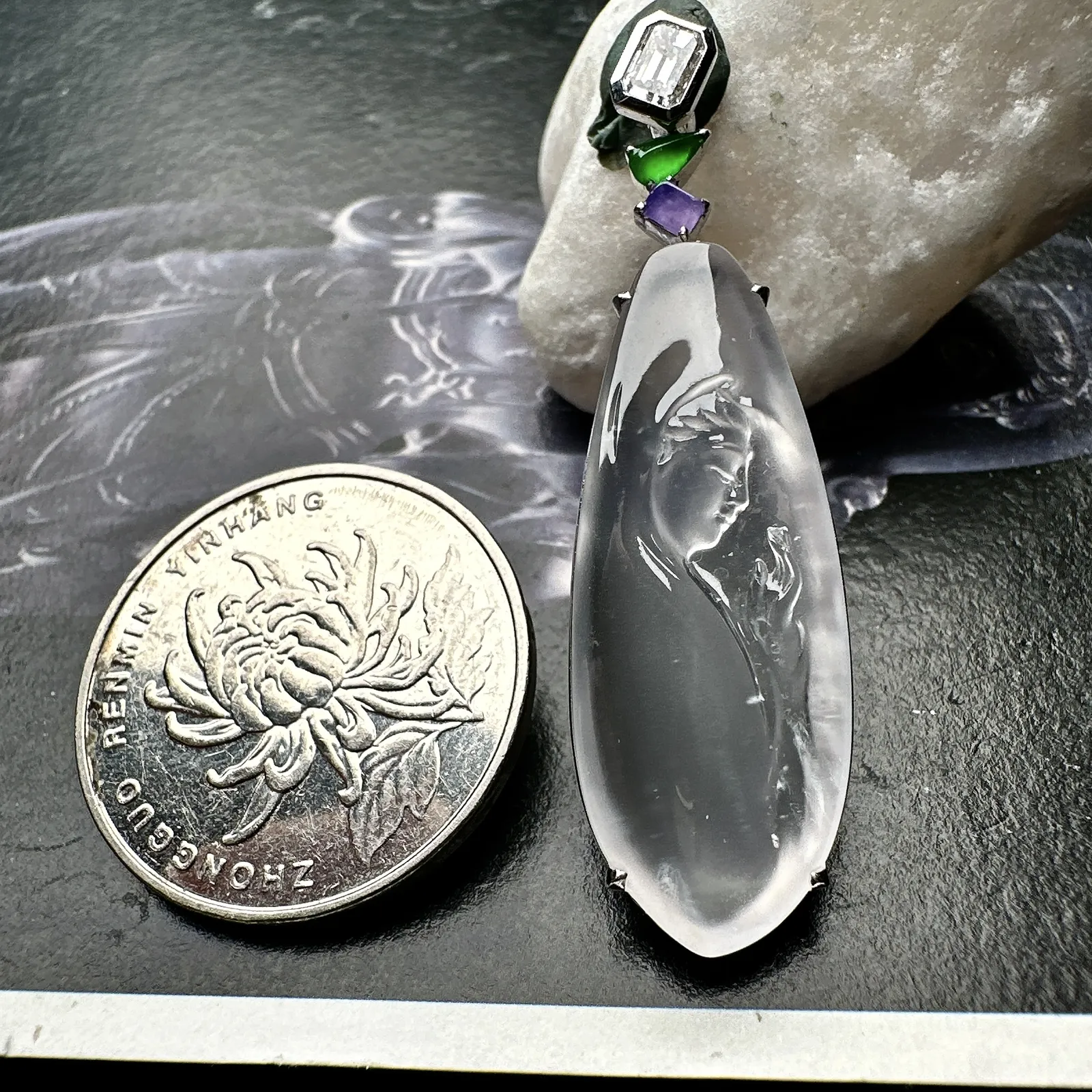 【玻璃种观音首吊坠】侧面像，料子通透闪亮，质地致密，种老起强胶感，玻璃光泽强烈。人物面部开脸生动，雕刻很精细，表情端庄祥和。料子纯净，18K金钻镶嵌，裸石尺寸33.3*13*2.8毫米