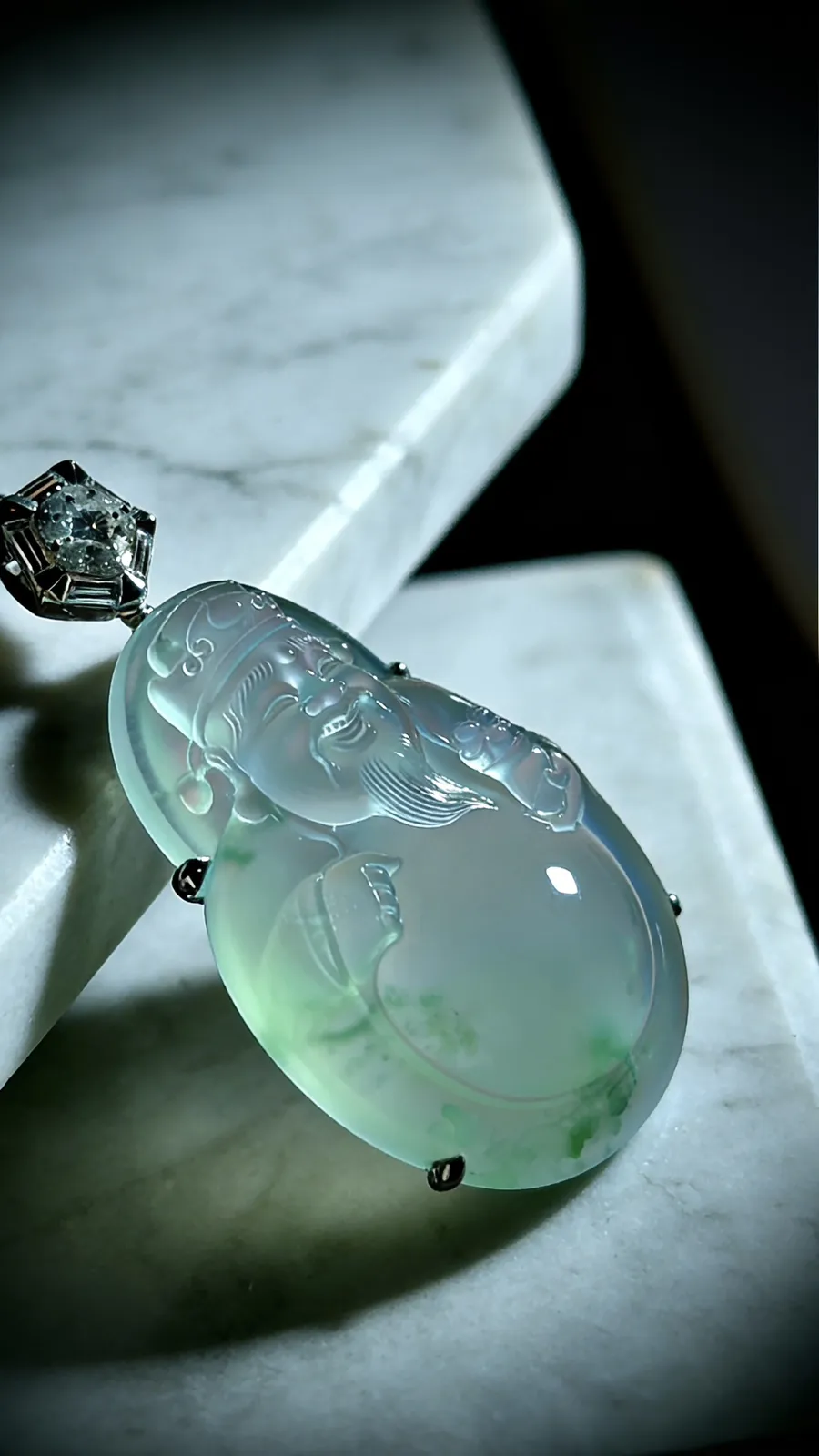 飘花【财神爷】，凝萃一方澄澈玉，
莹润通透如揽春溪在怀，花色轻拂似藏烟雨朦胧。
笑面财神笑意融，携福运财运来，
镶嵌与温润美玉相映成趣，
既是东方祥瑞的信物，亦是雅致天成的收藏，
佩之纳福招财，岁岁皆安。
作品裸石36.8-28.8-6.8mm，
整体46-29-10mm，14.38g，
18K金，南非钻