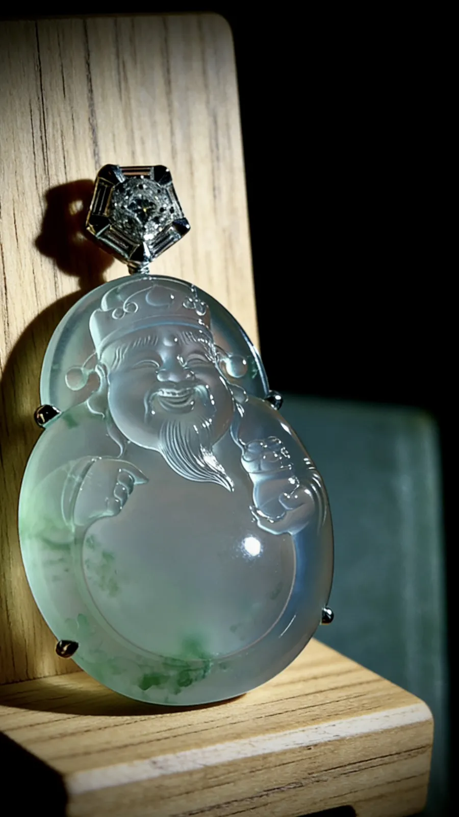 飘花【财神爷】，凝萃一方澄澈玉，
莹润通透如揽春溪在怀，花色轻拂似藏烟雨朦胧。
笑面财神笑意融，携福运财运来，
镶嵌与温润美玉相映成趣，
既是东方祥瑞的信物，亦是雅致天成的收藏，
佩之纳福招财，岁岁皆安。
作品裸石36.8-28.8-6.8mm，
整体46-29-10mm，14.38g，
18K金，南非钻