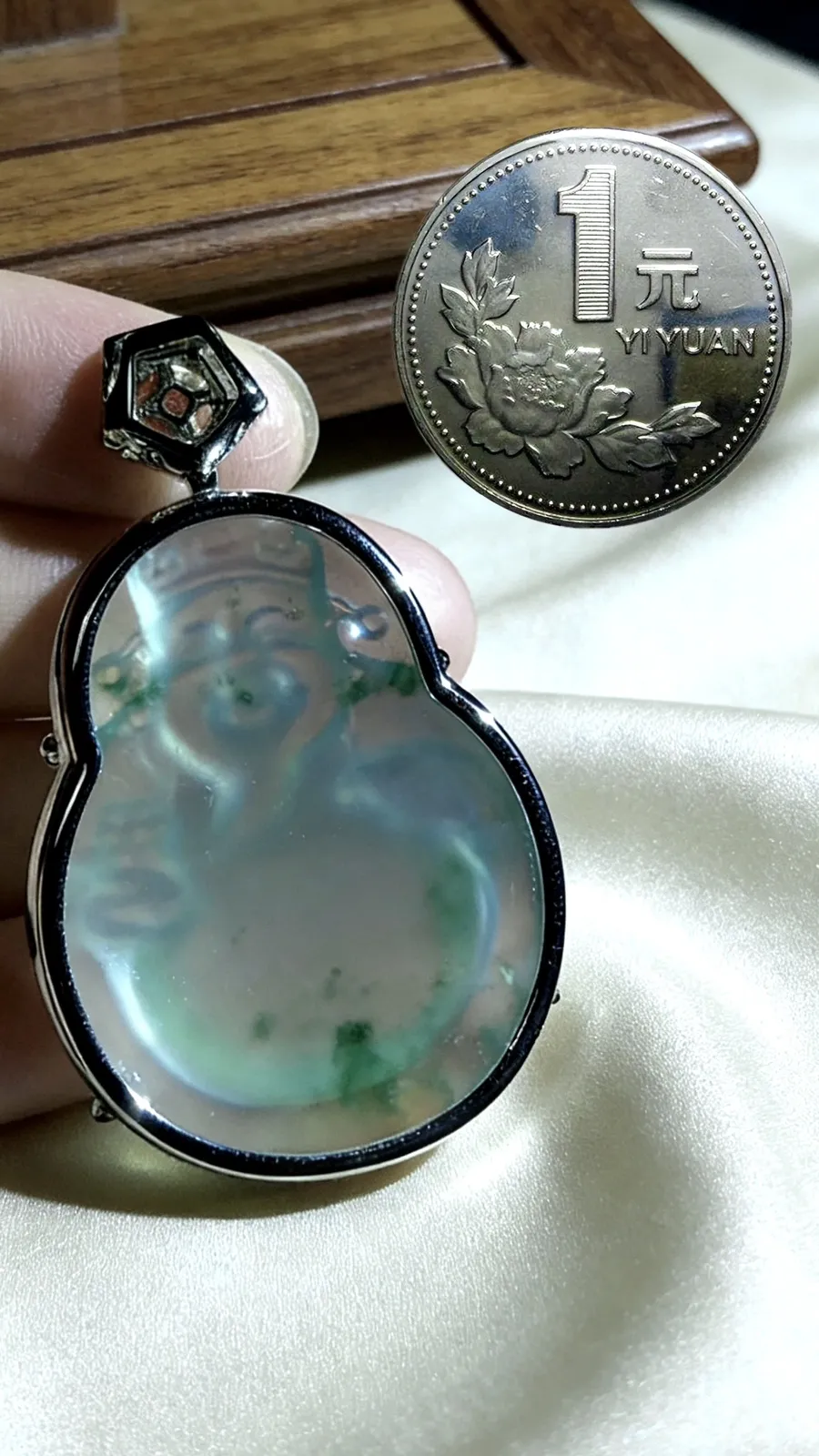 飘花【财神爷】，凝萃一方澄澈玉，
莹润通透如揽春溪在怀，花色轻拂似藏烟雨朦胧。
笑面财神笑意融，携福运财运来，
镶嵌与温润美玉相映成趣，
既是东方祥瑞的信物，亦是雅致天成的收藏，
佩之纳福招财，岁岁皆安。
作品裸石36.8-28.8-6.8mm，
整体46-29-10mm，14.38g，
18K金，南非钻