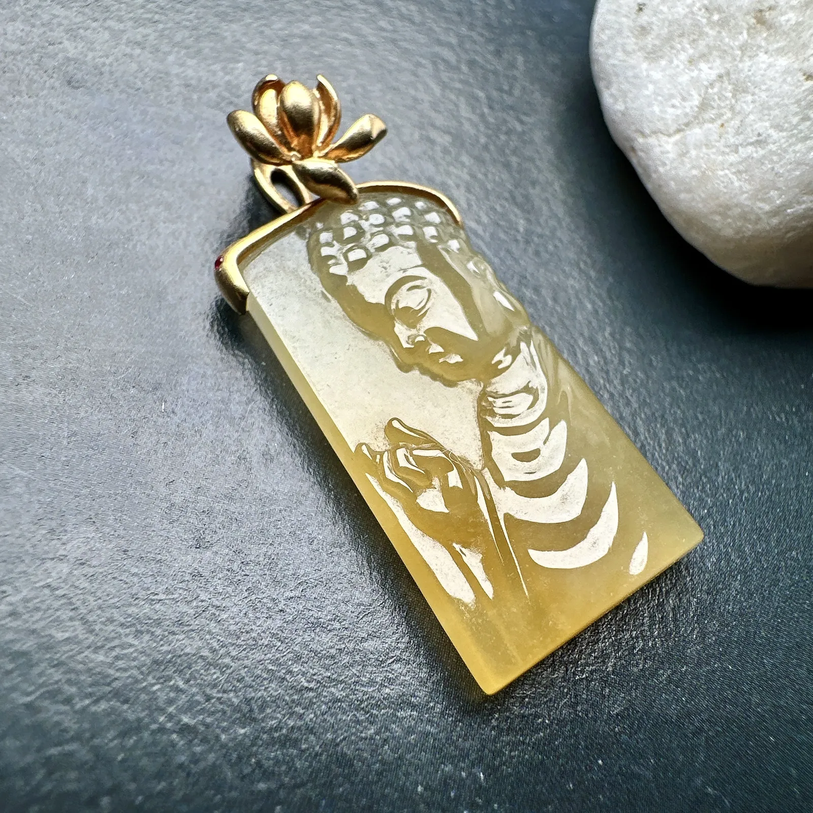 【冰种黄翡宝宝佛首吊坠】侧面像，料子通透闪亮，质地致密，雕刻很精细，18K金钻镶嵌，裸石尺寸26.1*14*4.5毫米