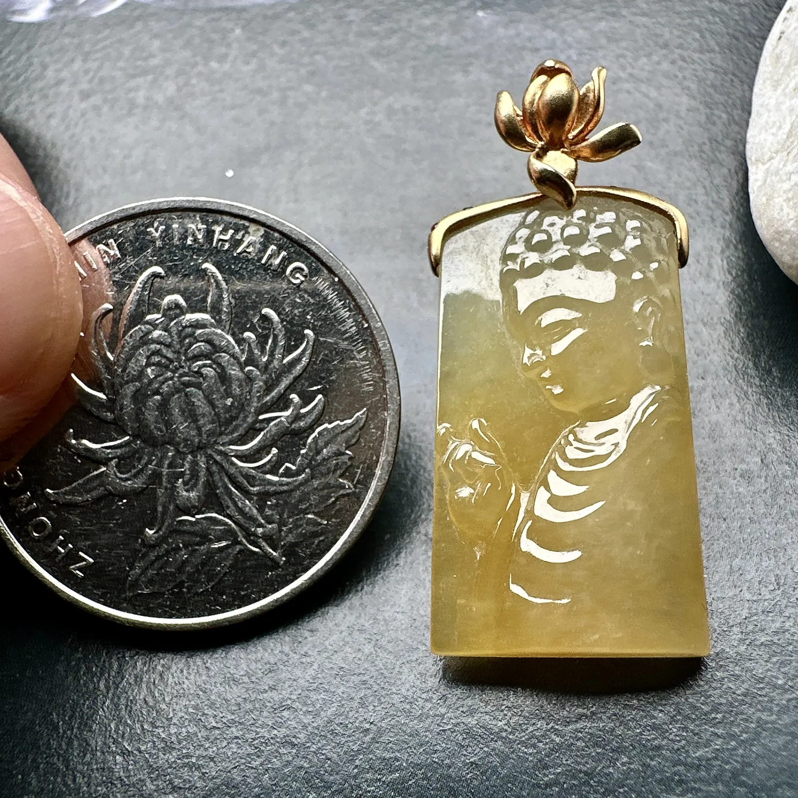 【冰种黄翡宝宝佛首吊坠】侧面像，料子通透闪亮，质地致密，雕刻很精细，18K金钻镶嵌，裸石尺寸26.1*14*4.5毫米