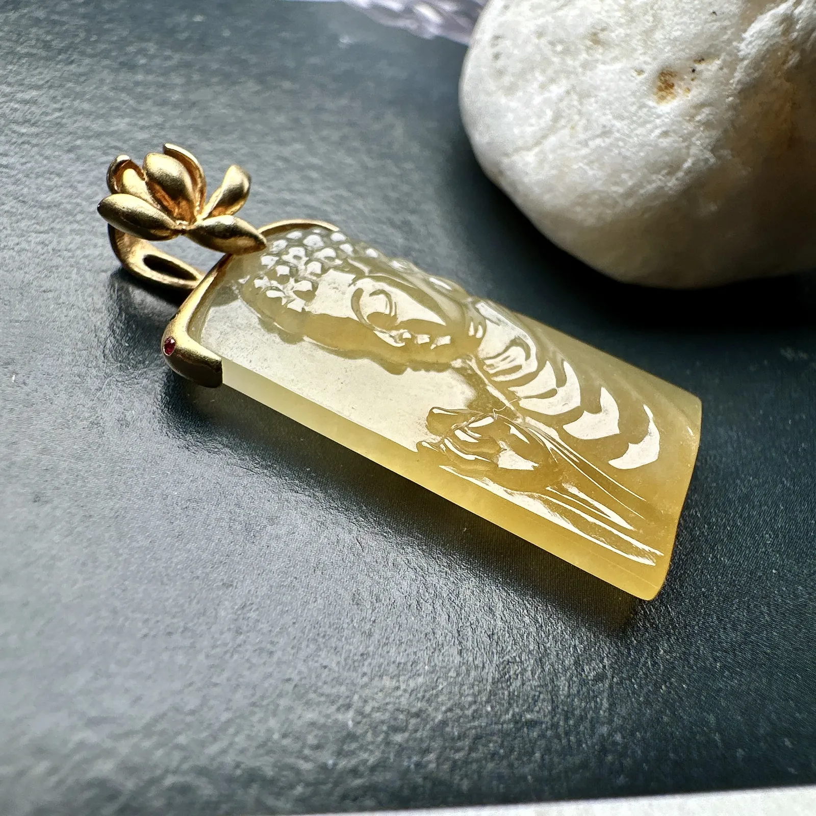 【冰种黄翡宝宝佛首吊坠】侧面像，料子通透闪亮，质地致密，雕刻很精细，18K金钻镶嵌，裸石尺寸26.1*14*4.5毫米