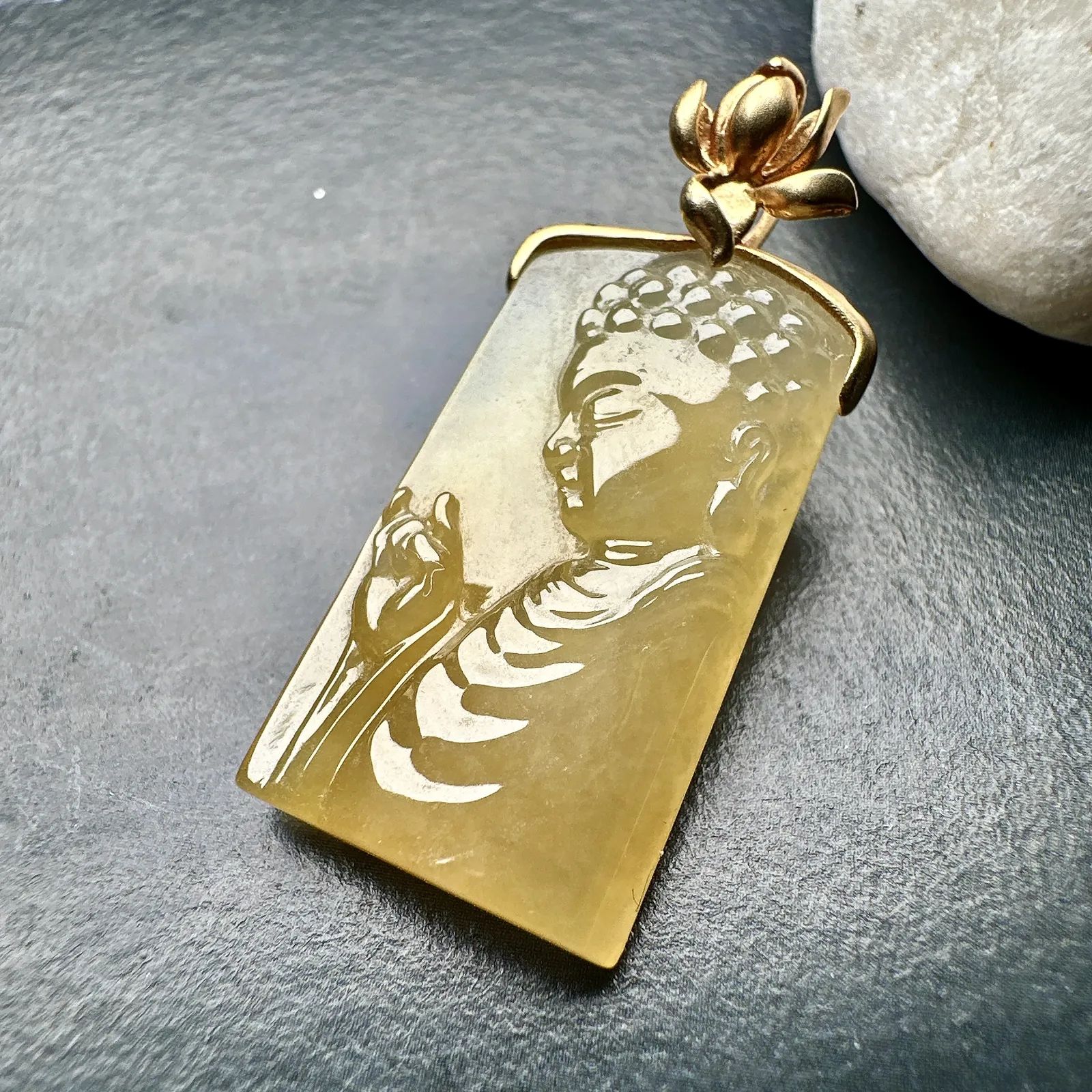 【冰种黄翡宝宝佛首吊坠】侧面像，料子通透闪亮，质地致密，雕刻很精细，18K金钻镶嵌，裸石尺寸26.1*14*4.5毫米