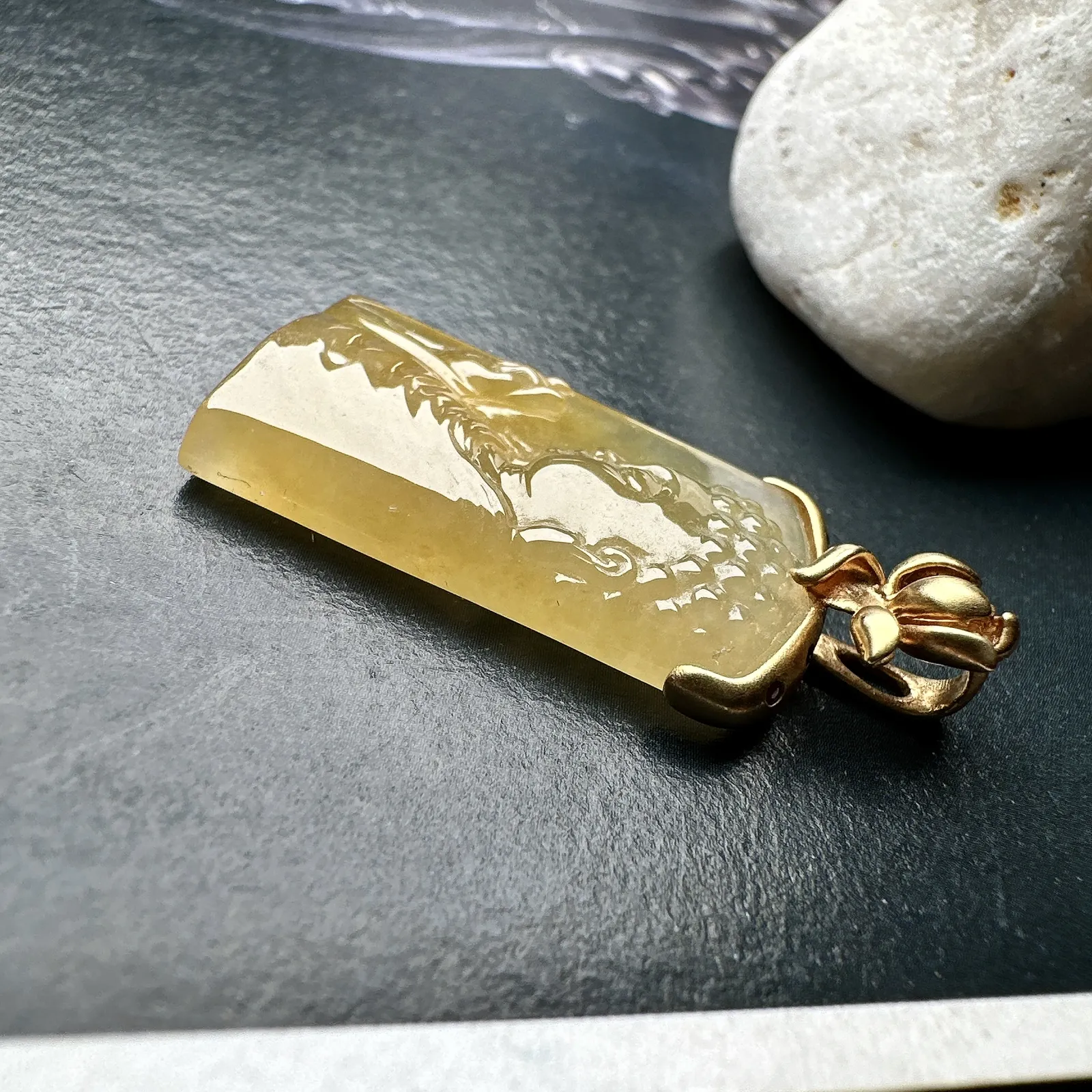 【冰种黄翡宝宝佛首吊坠】侧面像，料子通透闪亮，质地致密，雕刻很精细，18K金钻镶嵌，裸石尺寸26.1*14*4.5毫米