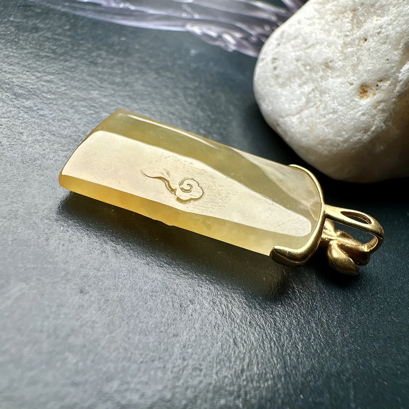 【冰种黄翡宝宝佛首吊坠】侧面像，料子通透闪亮，质地致密，雕刻很精细，18K金钻镶嵌，裸石尺寸26.1*14*4.5毫米