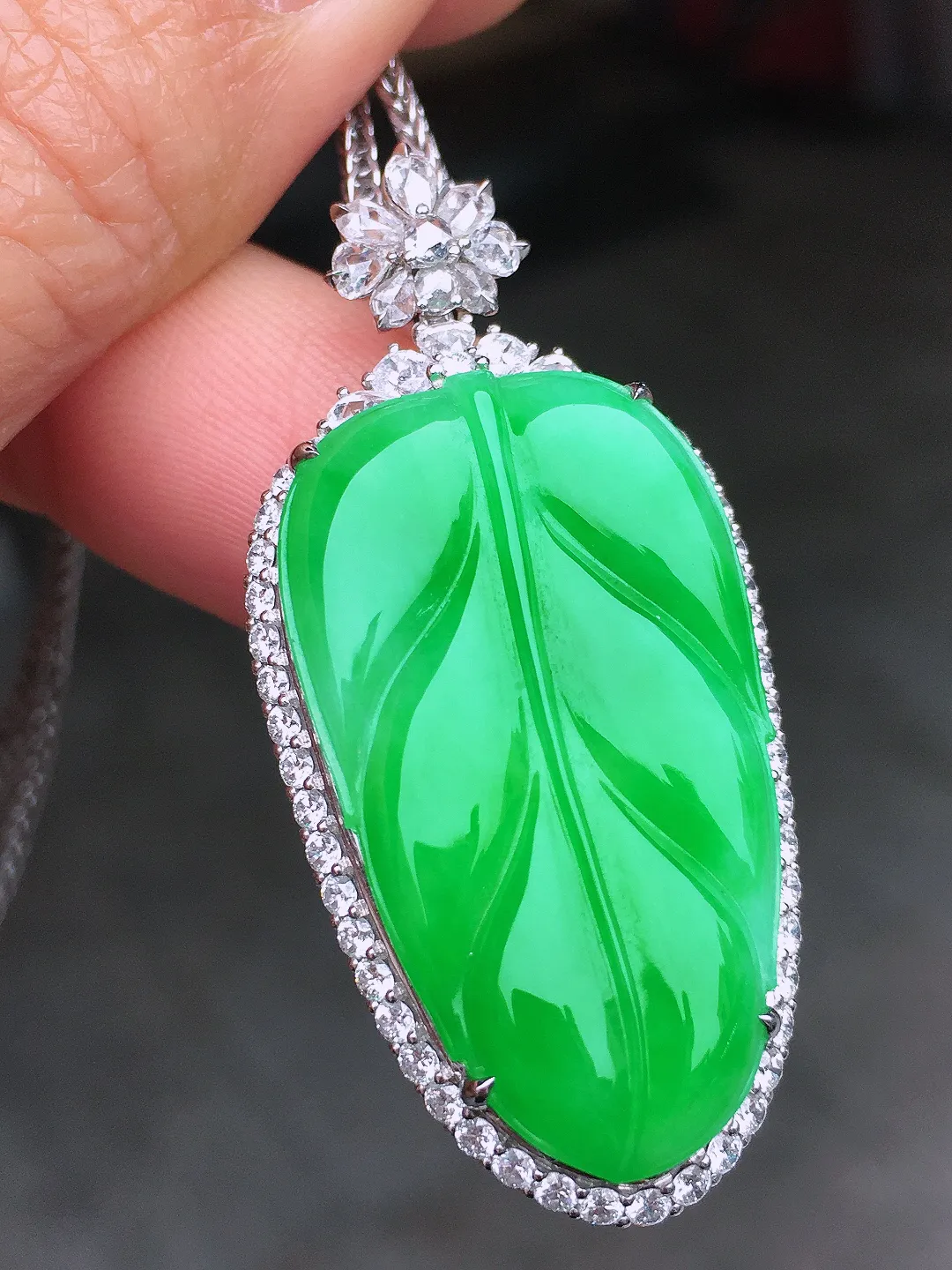 阳绿玉叶吊坠，色泽均匀艳丽，玉质细腻，荧光感超
强，饱满圆润，尽显优雅气质，18k
金豪华镶嵌