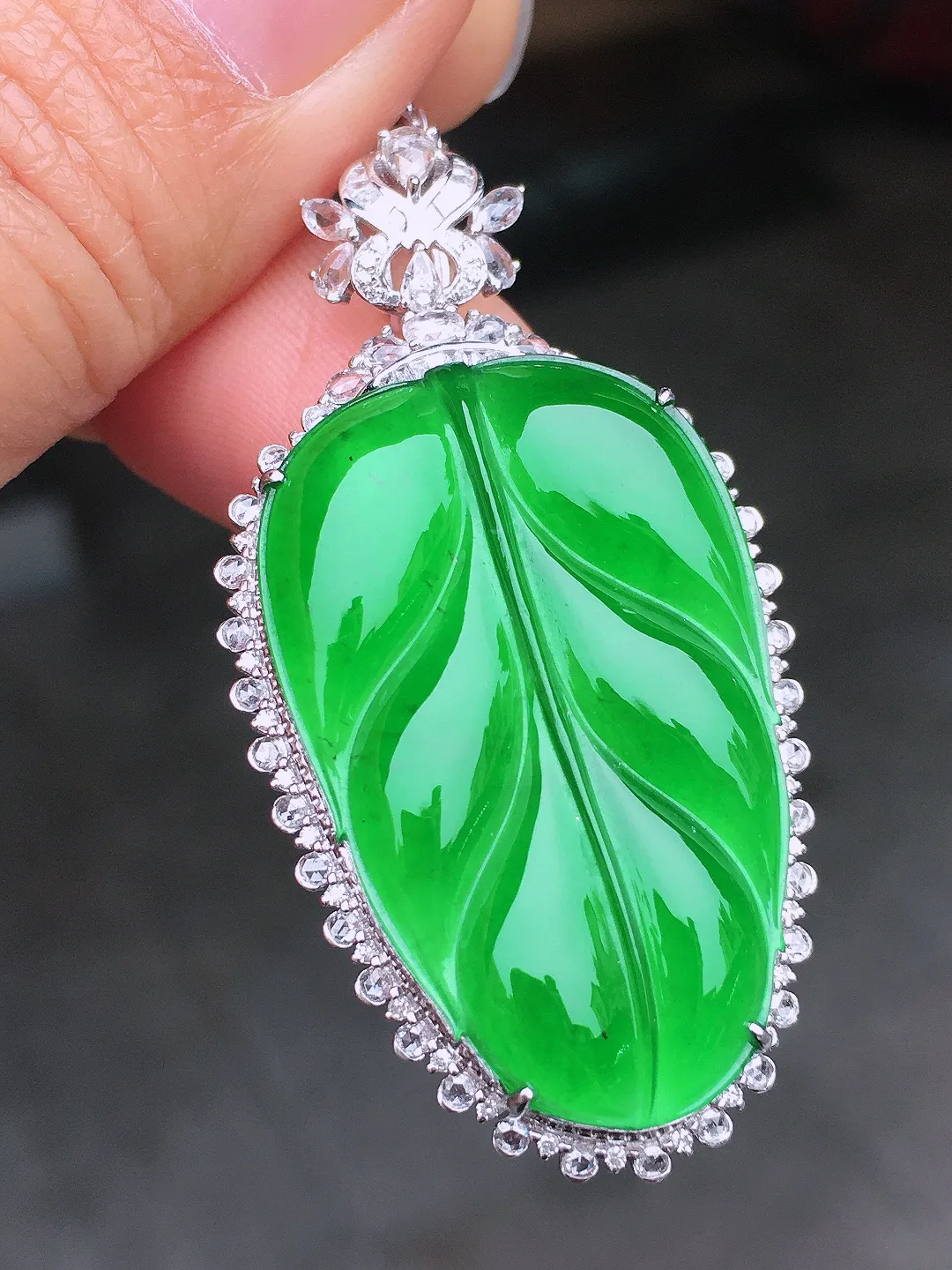 阳绿玉叶吊坠，色泽均匀艳丽，玉质细腻，荧光感超
强，饱满圆润，尽显优雅气质，18k
金豪华镶嵌