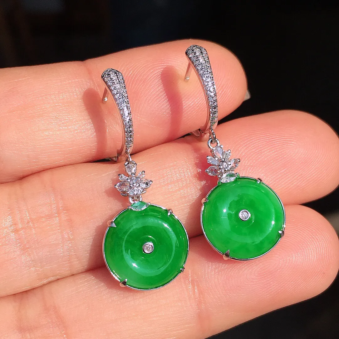 阳绿平安扣耳坠，色泽均匀艳丽，玉质细腻，荧光感超
强，饱满圆润，尽显优雅气质，18k
金豪华镶嵌