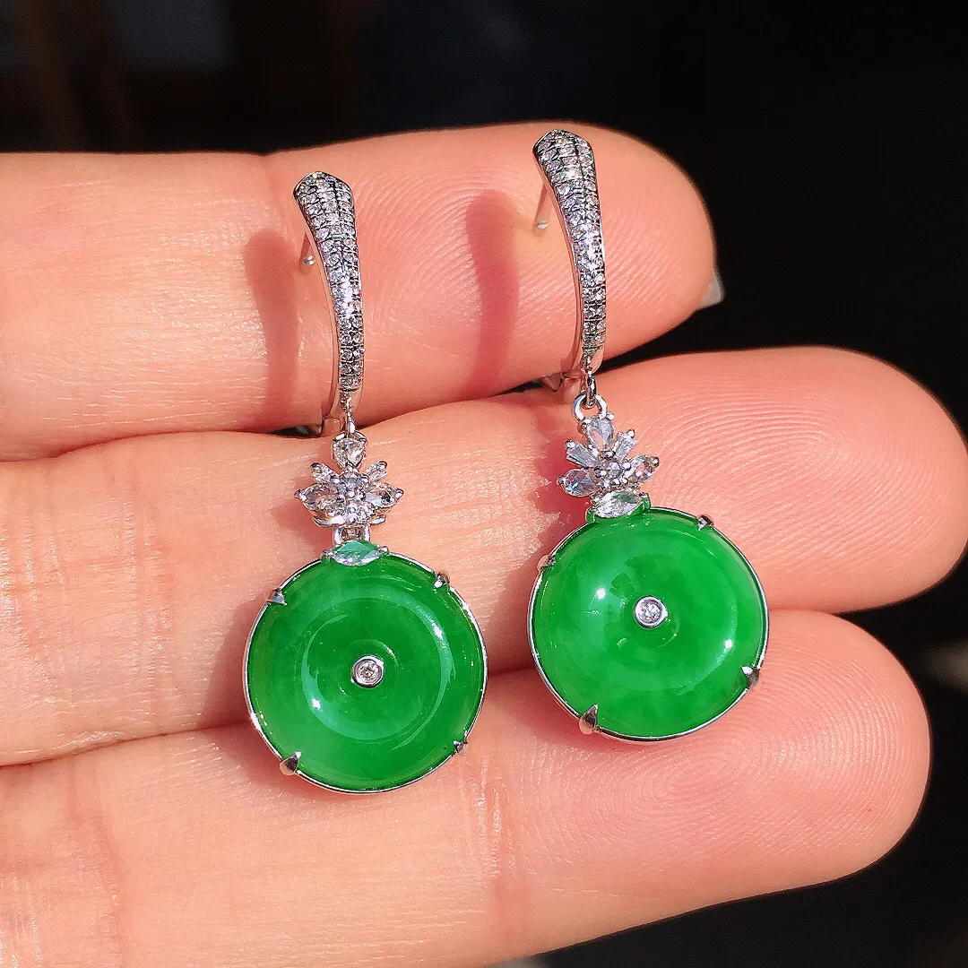 阳绿平安扣耳坠，色泽均匀艳丽，玉质细腻，荧光感超
强，饱满圆润，尽显优雅气质，18k
金豪华镶嵌