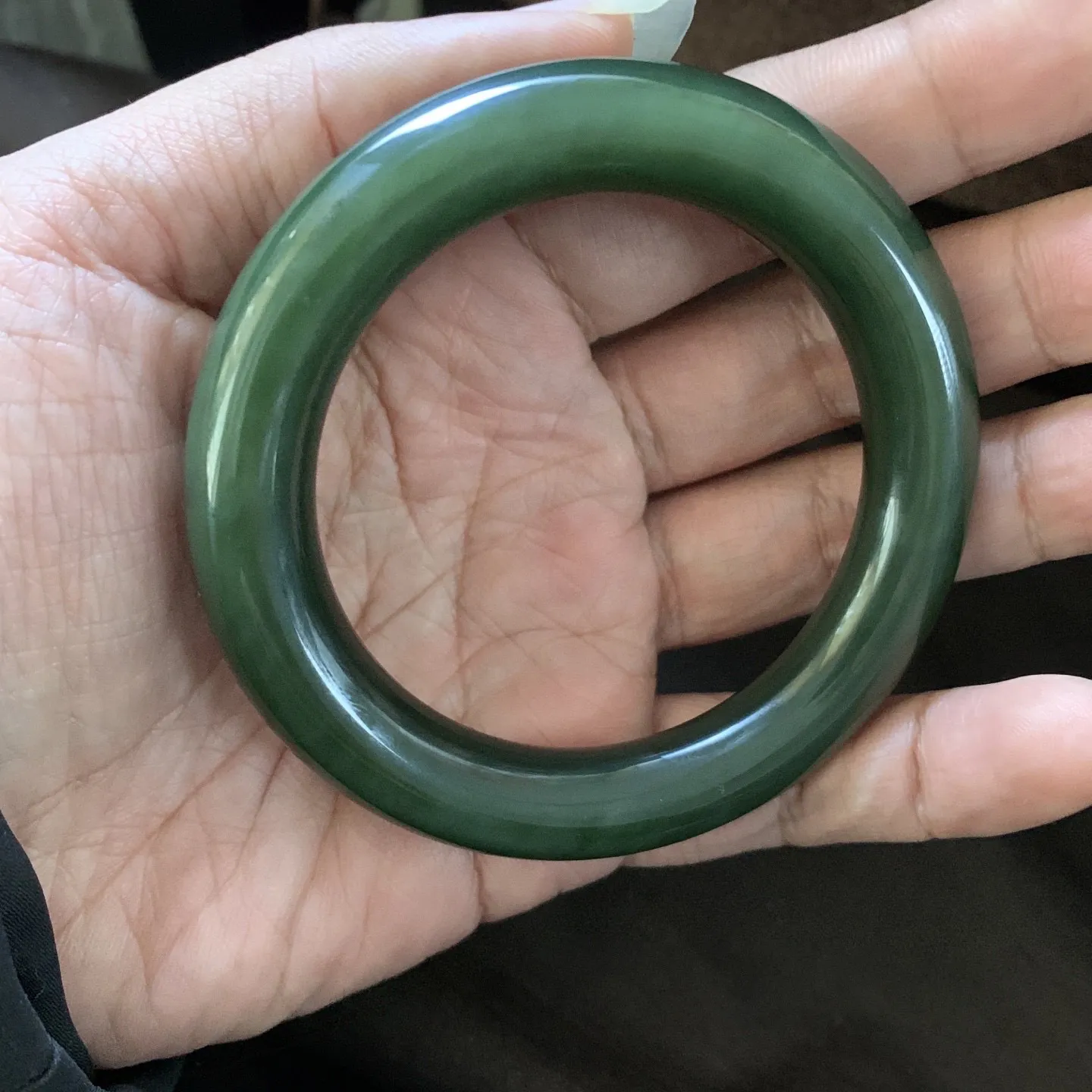 和田玉57圈口菠菜绿圆条手镯，镯型古朴典雅。在诗情画意的雨巷相遇，你是我腕间的一抹风情，有你眸有深情.清风荡漾湖间静水，我愿俯身低眉，在烟波涟漪处寻