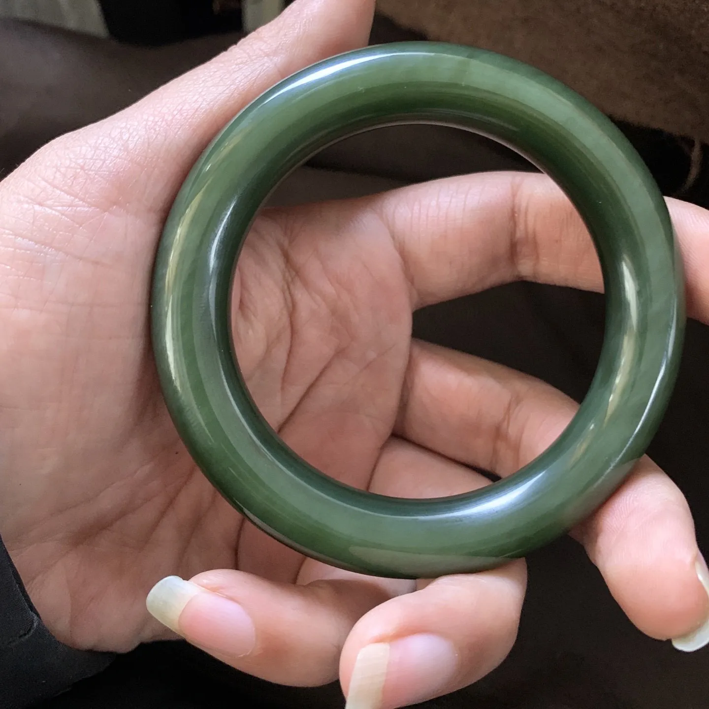 和田玉57圈口菠菜绿圆条手镯，镯型古朴典雅。在诗情画意的雨巷相遇，你是我腕间的一抹风情，有你眸有深情.清风荡漾湖间静水，我愿俯身低眉，在烟波涟漪处寻