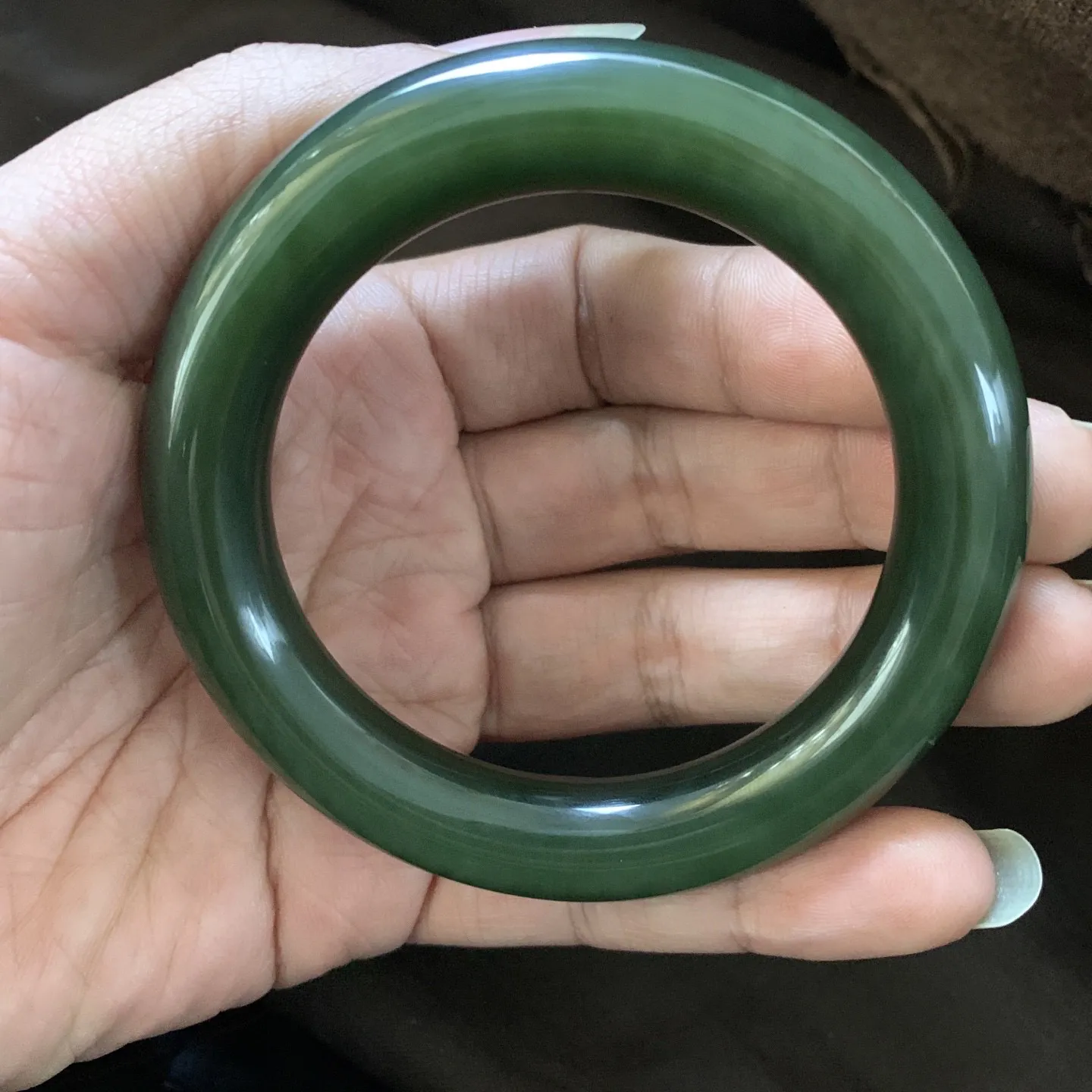 和田玉57圈口菠菜绿圆条手镯，镯型古朴典雅。在诗情画意的雨巷相遇，你是我腕间的一抹风情，有你眸有深情.清风荡漾湖间静水，我愿俯身低眉，在烟波涟漪处寻