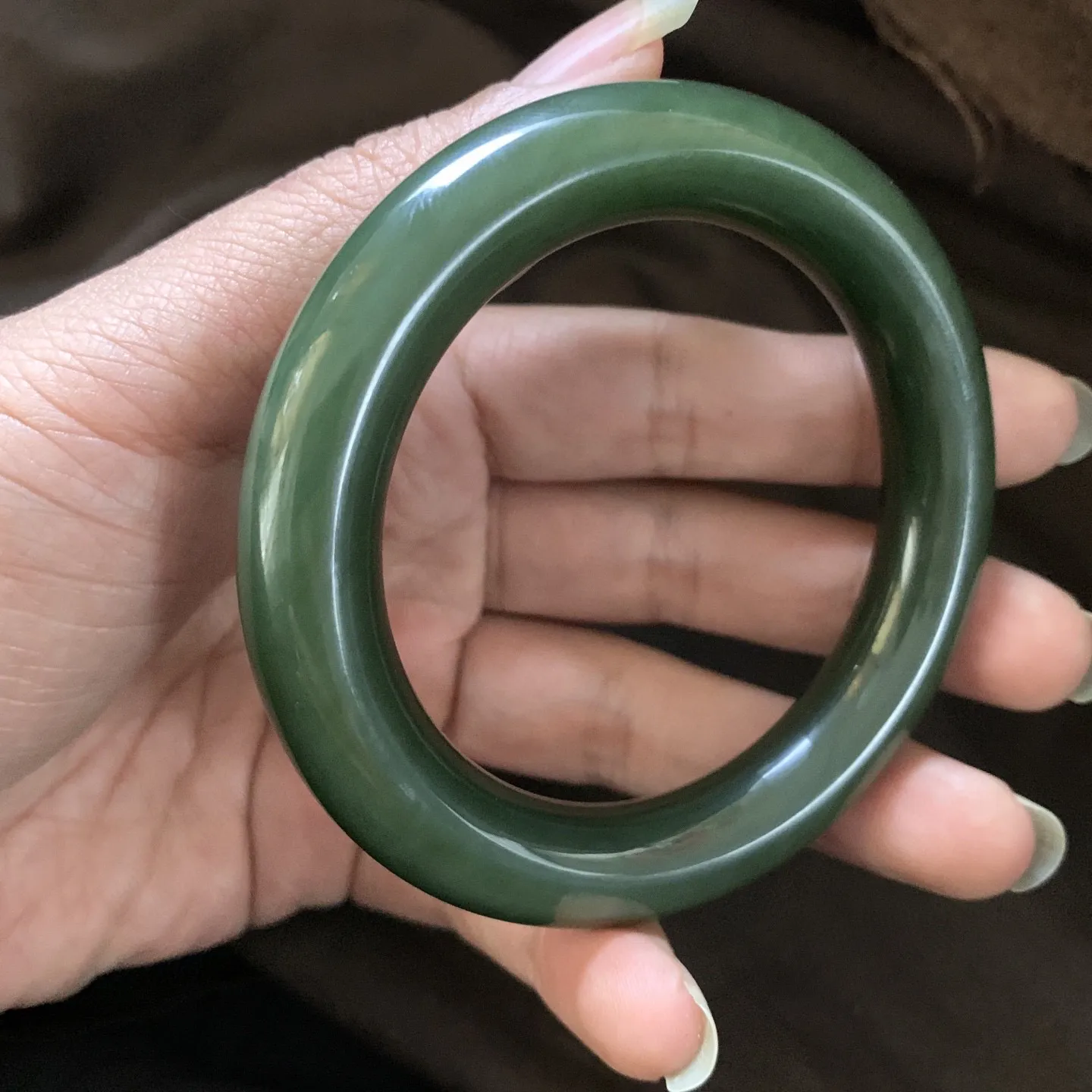 和田玉57圈口菠菜绿圆条手镯，镯型古朴典雅。在诗情画意的雨巷相遇，你是我腕间的一抹风情，有你眸有深情.清风荡漾湖间静水，我愿俯身低眉，在烟波涟漪处寻