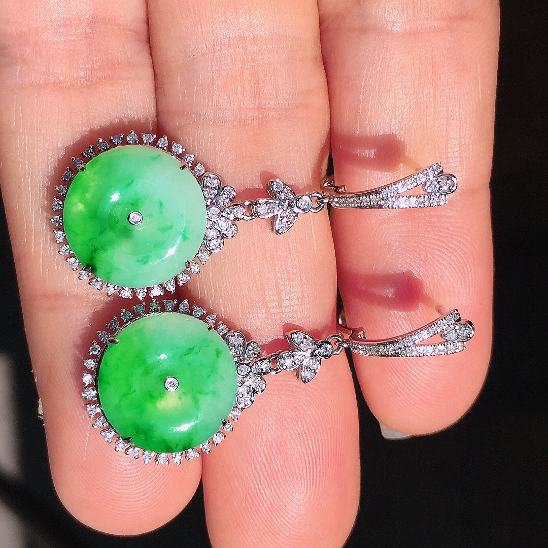 阳绿平安扣耳坠，色泽艳丽，玉质细腻，荧光感超
强，饱满圆润，尽显优雅气质，18k
金豪华镶嵌