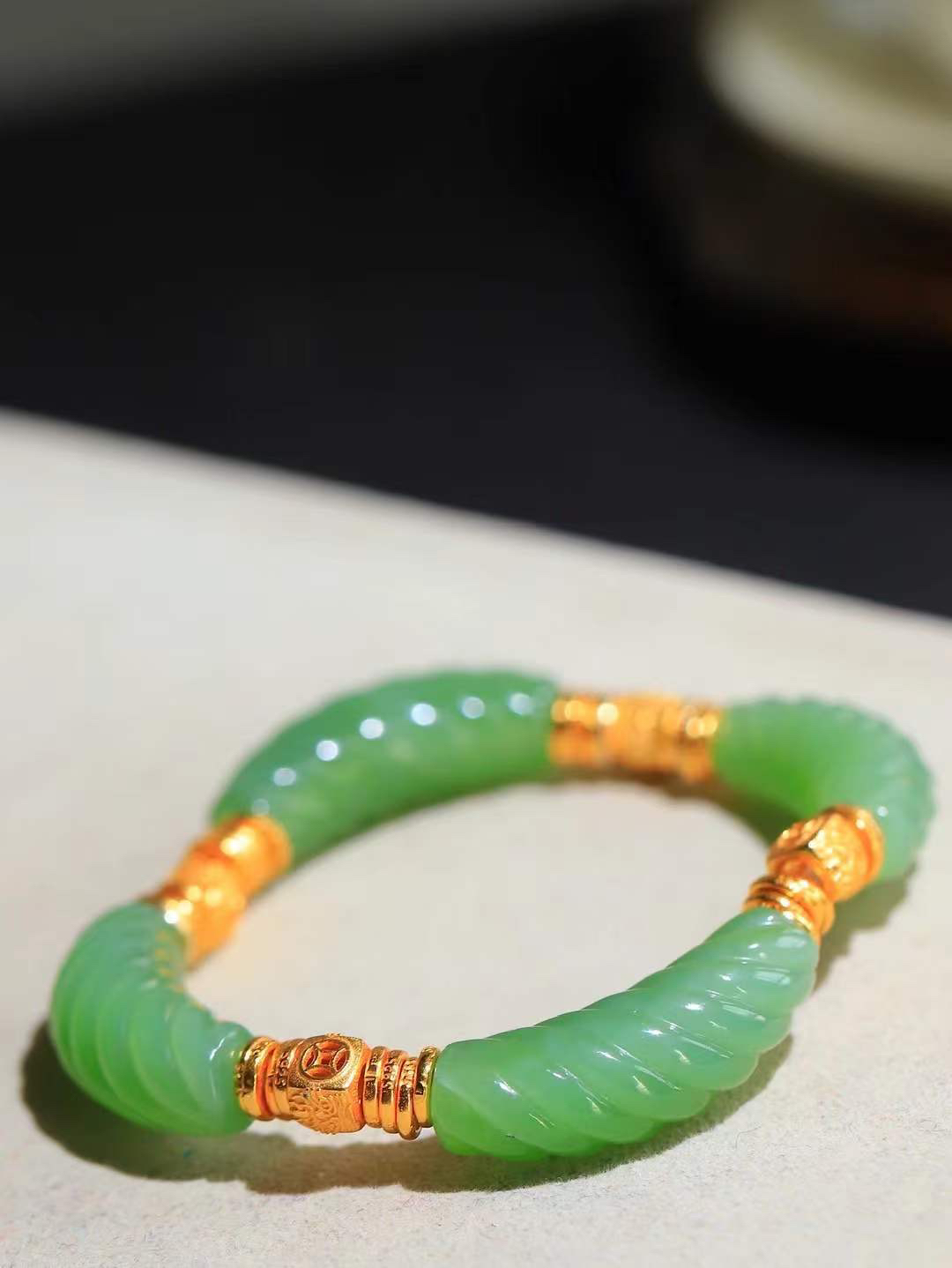 【绞丝纹.手串】

精品和田玉碧玉绞丝纹手串，以清润碧玉雕琢绞丝纹理，如碧丝萦回，寓意生机盎然、福运绵延；搭配古法金饰，铜钱纹藏招财进宝之意，吉祥纹纳平安顺遂之福。碧玉凝翠，金辉熠熠，既显东方清雅风骨，又藏富贵安康祈愿，是自戴祈福、赠友传情的雅致之选。重27.3克  尺寸取一30.2-9-10.2mm 89351200T