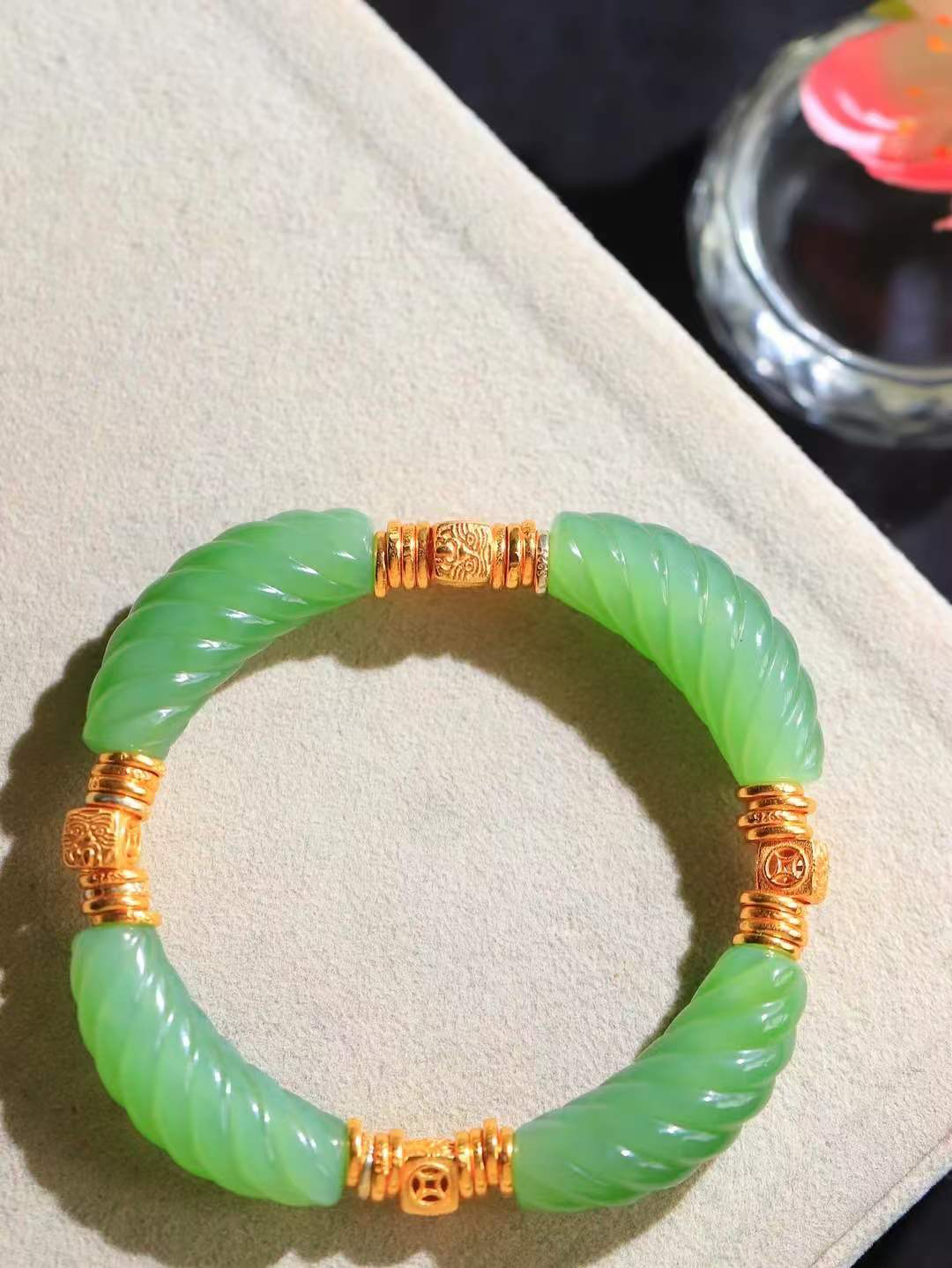 【绞丝纹.手串】

精品和田玉碧玉绞丝纹手串，以清润碧玉雕琢绞丝纹理，如碧丝萦回，寓意生机盎然、福运绵延；搭配古法金饰，铜钱纹藏招财进宝之意，吉祥纹纳平安顺遂之福。碧玉凝翠，金辉熠熠，既显东方清雅风骨，又藏富贵安康祈愿，是自戴祈福、赠友传情的雅致之选。重27.3克  尺寸取一30.2-9-10.2mm 89351200T