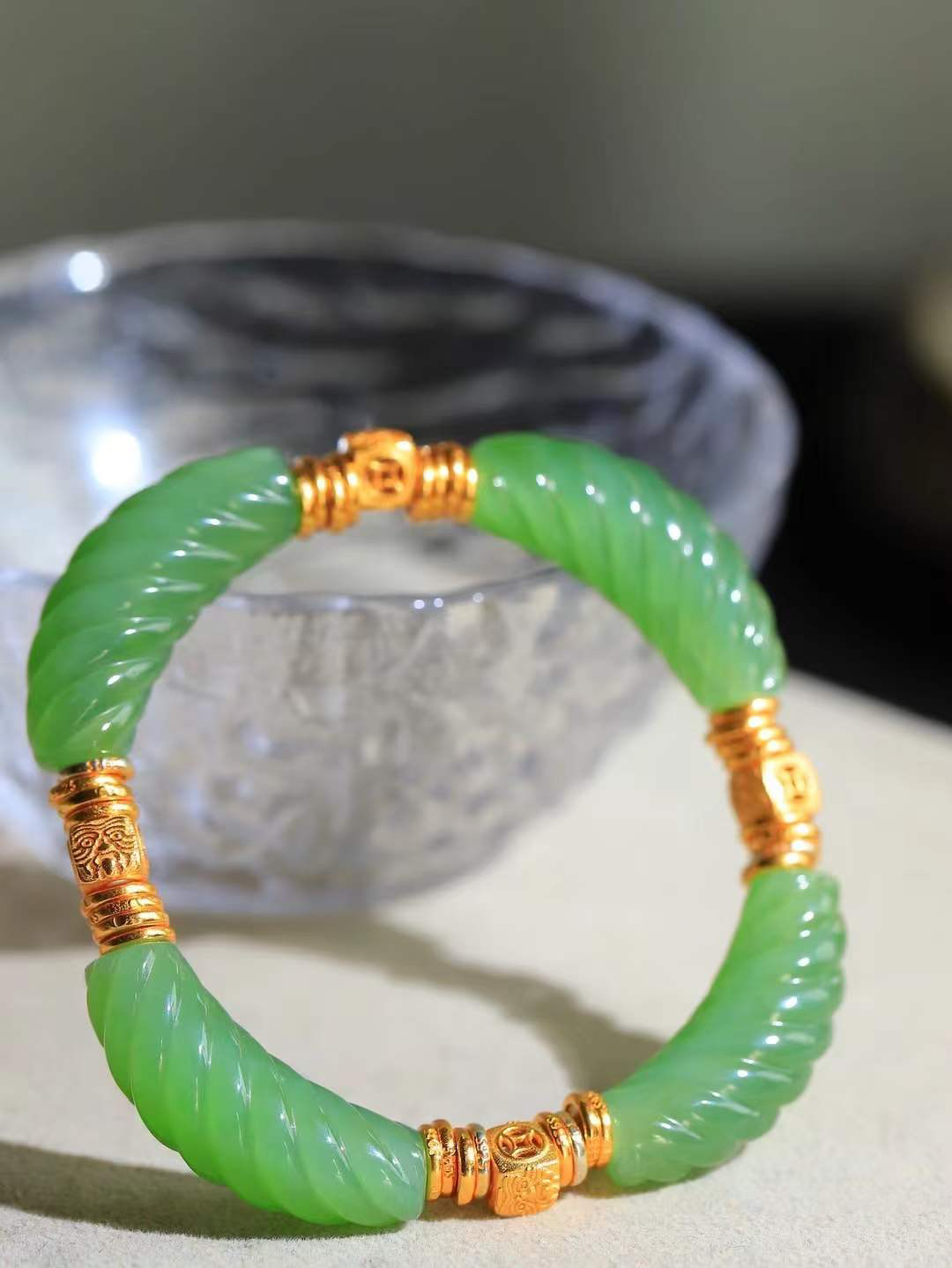 【绞丝纹.手串】

精品和田玉碧玉绞丝纹手串，以清润碧玉雕琢绞丝纹理，如碧丝萦回，寓意生机盎然、福运绵延；搭配古法金饰，铜钱纹藏招财进宝之意，吉祥纹纳平安顺遂之福。碧玉凝翠，金辉熠熠，既显东方清雅风骨，又藏富贵安康祈愿，是自戴祈福、赠友传情的雅致之选。重27.3克  尺寸取一30.2-9-10.2mm 89351200T