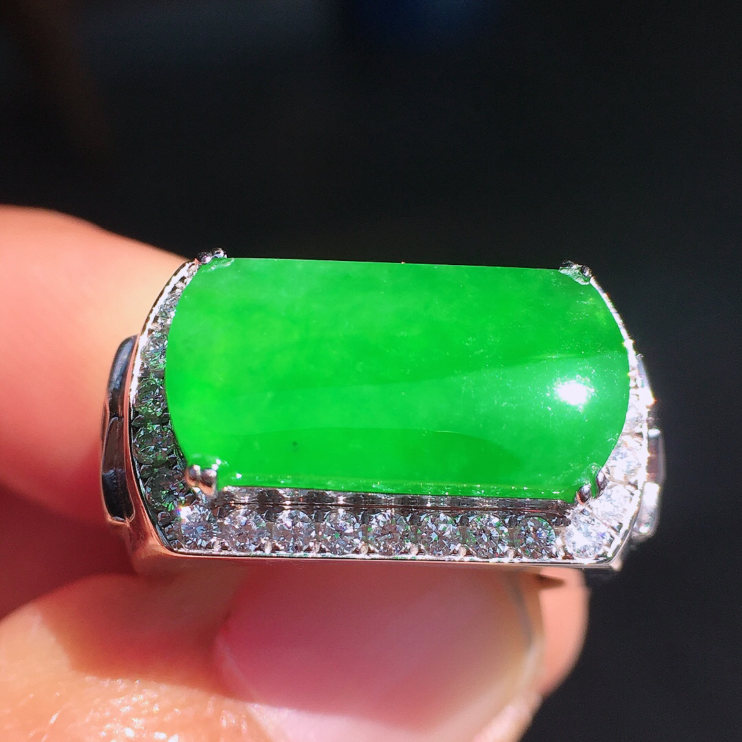 阳绿马鞍戒指，色泽均匀艳丽，玉质细腻，荧光感超
强，饱满圆润，尽显优雅气质，18k
金豪华镶嵌
