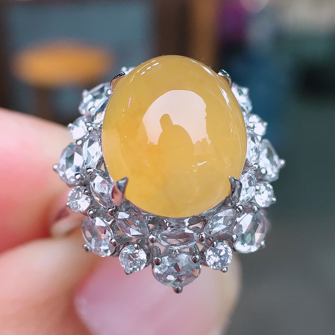 黄翡蛋面戒指，色泽均匀艳丽，玉质细腻，荧光感超
强，饱满圆润，尽显优雅气质，18k
金豪华镶嵌