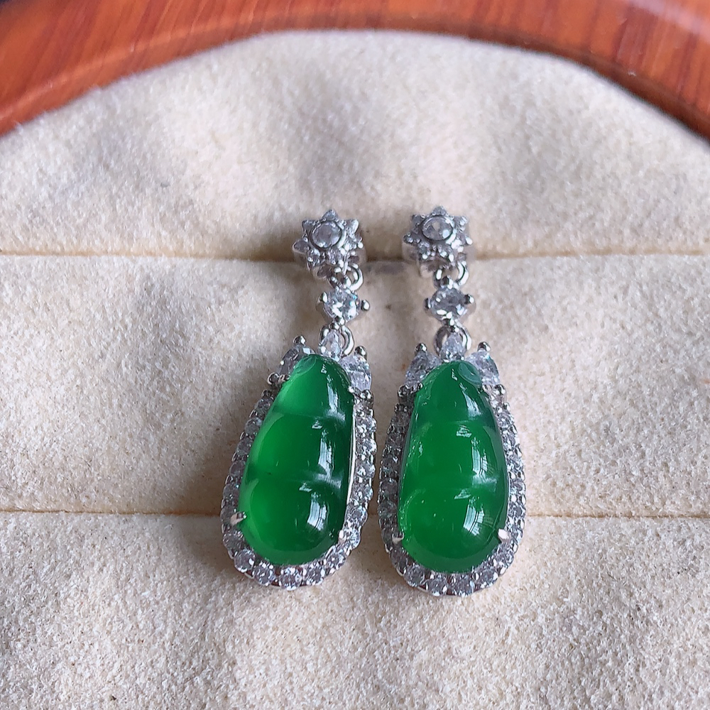 冰满绿翡翠925银镶嵌福豆耳钉，自然光实拍，翠色灵动，颜色漂亮，种老水足，品相佳，佩戴佳品！W481.8  取一整体尺寸：26.5-9-6.2mm  裸石尺寸：13.3-6.2mm