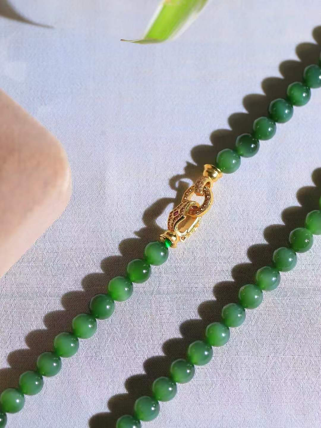 【珠圆玉润.项链】

精品和田玉碧玉猫眼珠圆玉润项链。这串碧玉项链垂落颈间，如把一汪春山绿意轻挽在身。玉色温润，每一颗圆珠都裹着圆满如意的期许，仿金扣轻缀，不事张扬却自有风骨。日常佩戴，是与草木同息的诗意，也是藏在细节里的安然与欢喜。重38.6克  尺寸取一5.9mm  21401466T