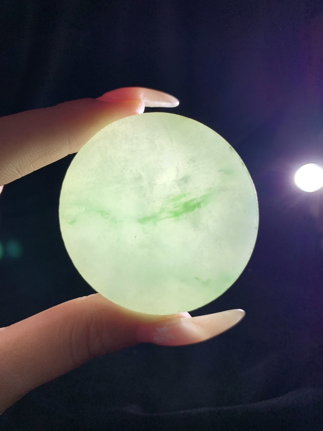 冰飘花 /牌子料/镯心料/特色料，可做牌子、人物、山水、动物、花件……等推荐参考，52.2-13.9，96.4克，材料优选，一圆清月凝冰魄，一缕飘翠画山川，这枚冰飘花翡翠圆牌胚料，质地温润莹净、水头灵透清亮，底色如月光铺洒般柔和淡雅，一抹浓绿飘花如远山含黛、似流水行舟，在素净玉面晕染出写意山水般的灵动意境，玉肉细腻胶润、品相规整圆满，稍加匠心雕琢，便可打磨成平安无事圆牌、怀古素圈、意境山水圆佩等雅致挂件，圆形象征圆满顺遂、团圆无忧，灵动飘花寓意前程舒展、生机绵延、福气生生不息气韵沉静温婉，佩戴可护佑岁岁平安、万事周全、福运圆圆满满、一生安稳无忧。