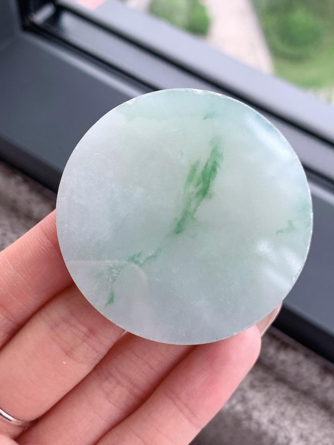 冰飘花 /牌子料/镯心料/特色料，可做牌子、人物、山水、动物、花件……等推荐参考，52.2-13.9，96.4克，材料优选，一圆清月凝冰魄，一缕飘翠画山川，这枚冰飘花翡翠圆牌胚料，质地温润莹净、水头灵透清亮，底色如月光铺洒般柔和淡雅，一抹浓绿飘花如远山含黛、似流水行舟，在素净玉面晕染出写意山水般的灵动意境，玉肉细腻胶润、品相规整圆满，稍加匠心雕琢，便可打磨成平安无事圆牌、怀古素圈、意境山水圆佩等雅致挂件，圆形象征圆满顺遂、团圆无忧，灵动飘花寓意前程舒展、生机绵延、福气生生不息气韵沉静温婉，佩戴可护佑岁岁平安、万事周全、福运圆圆满满、一生安稳无忧。