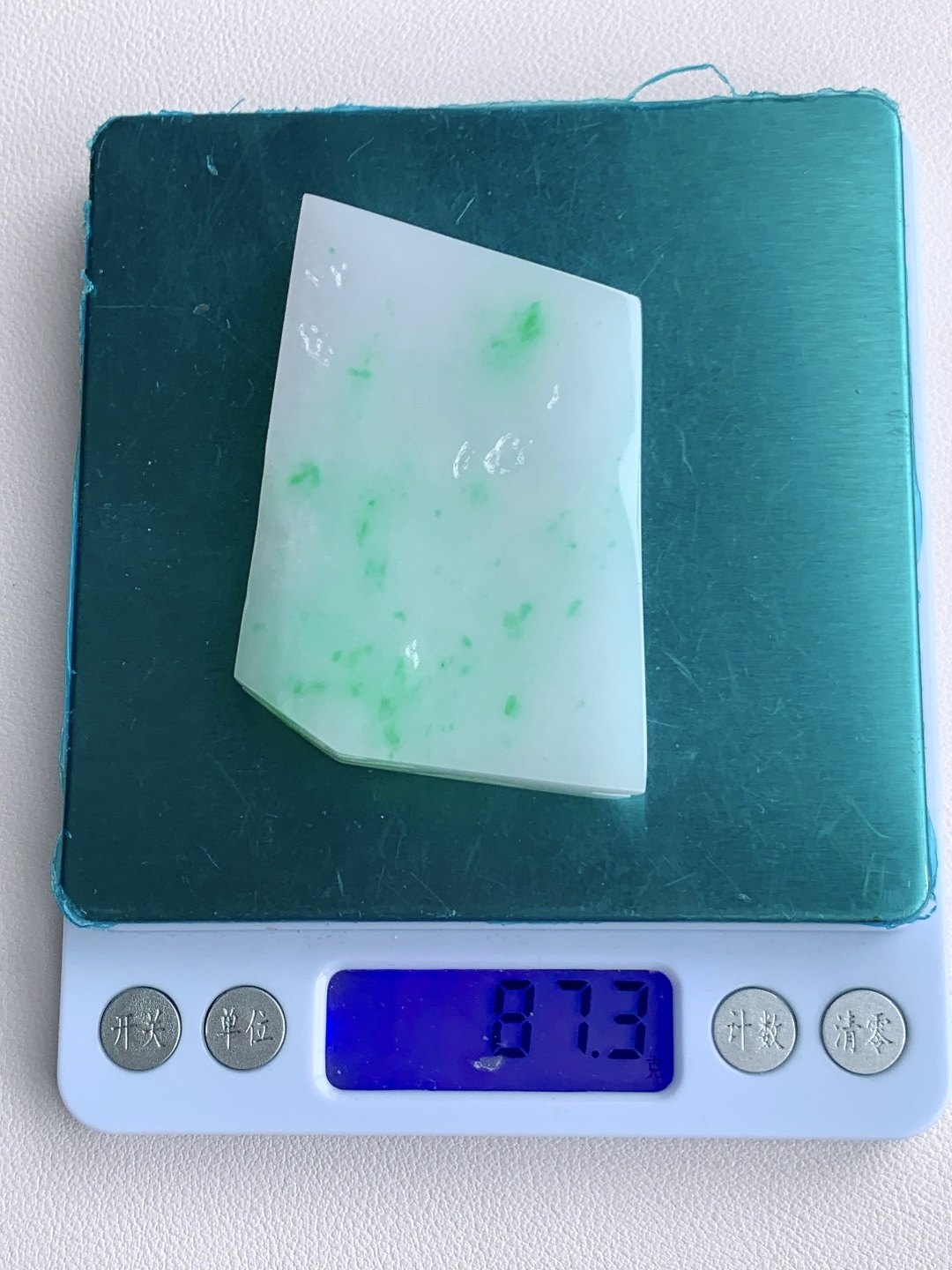 飘绿花/冰飘花/牌子料/片料/板料/特色料，可做牌子、人物、山水、动物、花件……等推荐参考，67.7-49.6-10.8，87.3克，材料优选，白底凝霜藏清润，翠点浮星蕴生机，这件白底青翡翠片料，底色莹白胜霜、细腻致密，如素绢般洁净温润，一抹抹阳绿灵动点缀、似星雨散落其间，色根鲜明、鲜阳灵动水头充足、胶感满满，经精工随形俏色雕琢，可打造为平安无事素牌、清雅山水牌、灵动瑞兽挂件等雅致佳作，白底寓意清净安宁、护主、顺遂无忧，翠点象征生机常伴、财运亨通、福禄常驻自带清新明快的氛围感，上手佩戴清爽百搭，既显温润雅致的气质，更承载着岁岁安康、前程明朗、福运绵延的美好祈愿。