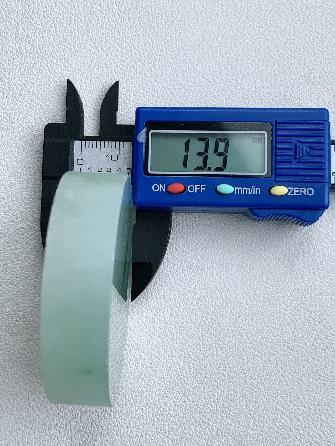 冰飘花 /牌子料/镯心料/特色料，可做牌子、人物、山水、动物、花件……等推荐参考，52.2-13.9，96.4克，材料优选，一圆清月凝冰魄，一缕飘翠画山川，这枚冰飘花翡翠圆牌胚料，质地温润莹净、水头灵透清亮，底色如月光铺洒般柔和淡雅，一抹浓绿飘花如远山含黛、似流水行舟，在素净玉面晕染出写意山水般的灵动意境，玉肉细腻胶润、品相规整圆满，稍加匠心雕琢，便可打磨成平安无事圆牌、怀古素圈、意境山水圆佩等雅致挂件，圆形象征圆满顺遂、团圆无忧，灵动飘花寓意前程舒展、生机绵延、福气生生不息气韵沉静温婉，佩戴可护佑岁岁平安、万事周全、福运圆圆满满、一生安稳无忧。