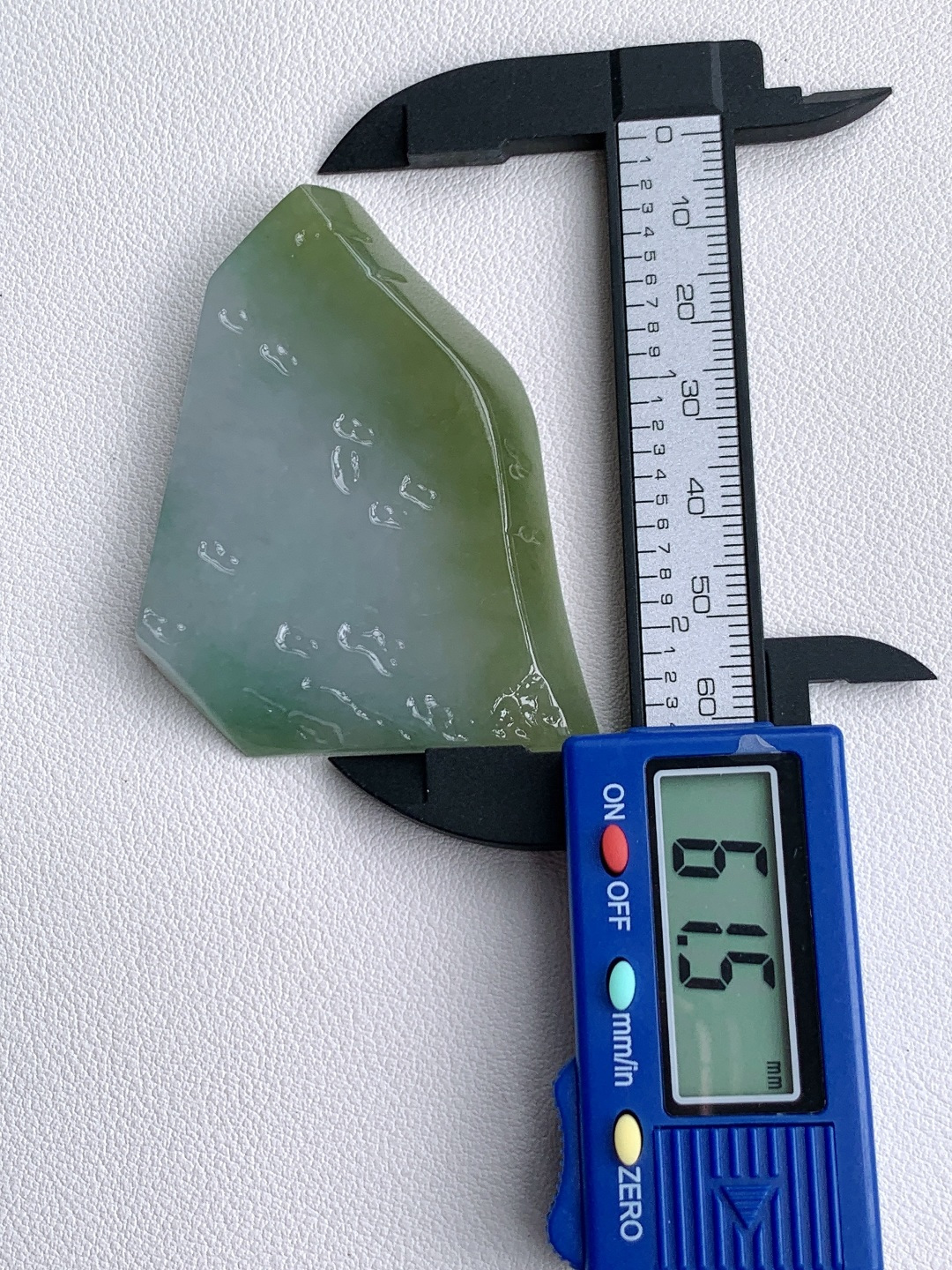 冰晴绿/冰飘花/牌子料/片料/板料/特色料，可做牌子、人物、山水、动物、花件……等推荐参考，61.5-44.9-7.4，43克，山衔浅黛凝清露，玉染轻烟蕴翠痕，这块冰润晴底带彩翡翠料子，底色温润通透如月光铺洒，边角晕染暖柔浅黄，一抹飘花翠色灵秀点缀其间，玉质细腻莹亮、水头充盈饱满，稍加匠心俏色精雕，便可化作山水意境牌、平安无事牌、悟道禅意挂件等雅致形制，浅暖翡色寓意温润纳福、和顺长久，点点翠花象征生机盎然、顺遂无忧自带清逸空灵的静谧氛围感，佩戴间衬得气质温润淡然，亦承载着山河安然、岁岁平顺、福运绵长的美好祈愿。