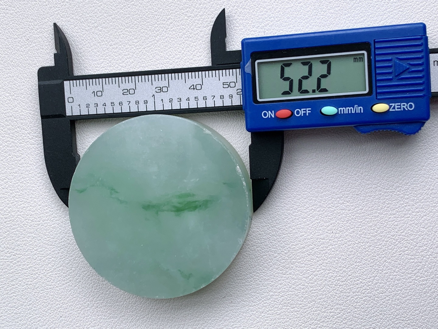 冰飘花 /牌子料/镯心料/特色料，可做牌子、人物、山水、动物、花件……等推荐参考，52.2-13.9，96.4克，材料优选，一圆清月凝冰魄，一缕飘翠画山川，这枚冰飘花翡翠圆牌胚料，质地温润莹净、水头灵透清亮，底色如月光铺洒般柔和淡雅，一抹浓绿飘花如远山含黛、似流水行舟，在素净玉面晕染出写意山水般的灵动意境，玉肉细腻胶润、品相规整圆满，稍加匠心雕琢，便可打磨成平安无事圆牌、怀古素圈、意境山水圆佩等雅致挂件，圆形象征圆满顺遂、团圆无忧，灵动飘花寓意前程舒展、生机绵延、福气生生不息气韵沉静温婉，佩戴可护佑岁岁平安、万事周全、福运圆圆满满、一生安稳无忧。