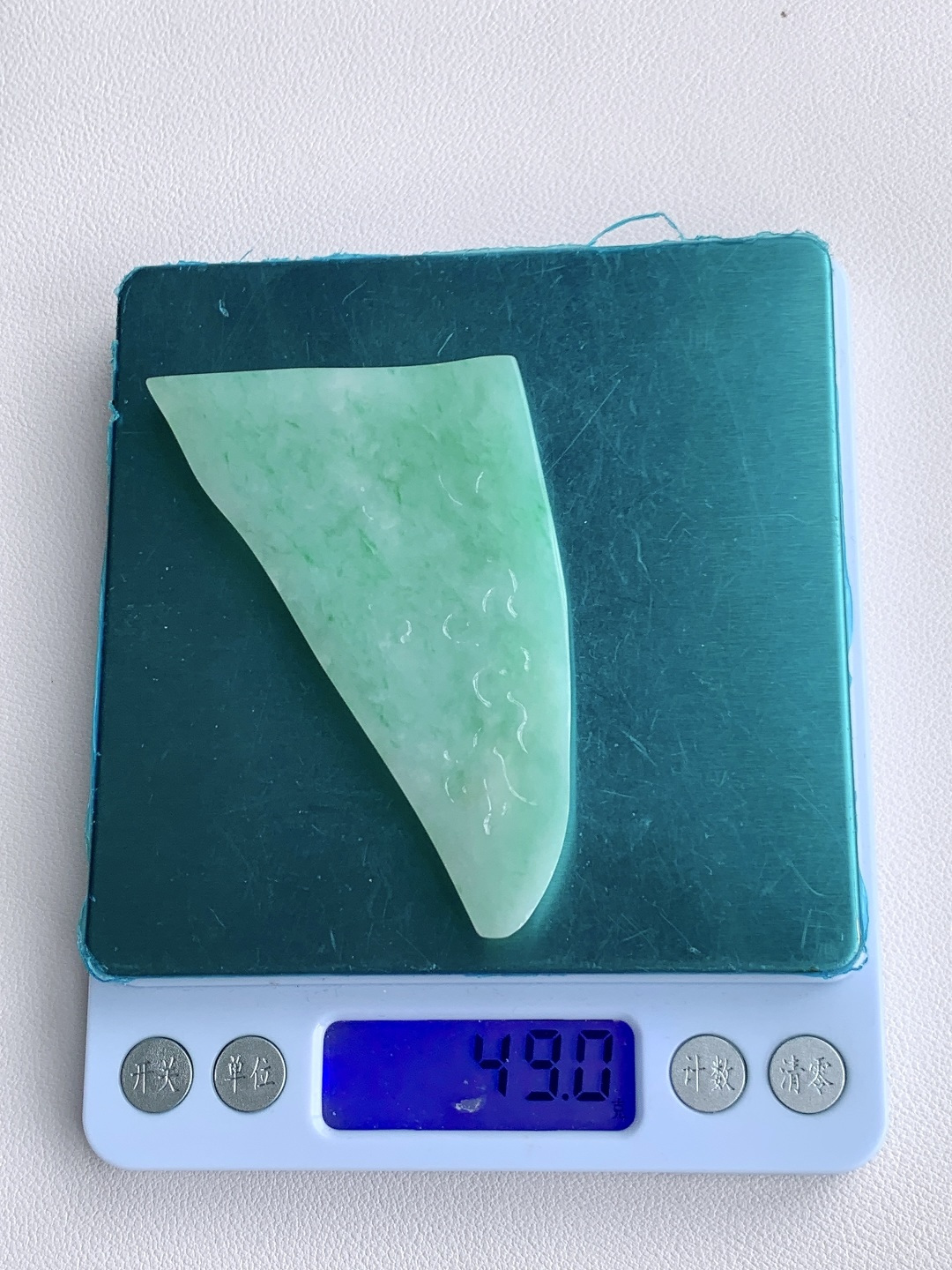 飘绿花/牌子料/片料/板料/特色料，可做牌子、人物、山水、动物、花件……等推荐参考，77.3-55-6.8，49克，烟青漫染春山色，柔翠轻铺玉骨温，这块冰润飘绿翡翠随形片料，底色清润通透、如春水漾漾般柔和匀净，鲜灵翠色如烟云晕染、丝丝缕缕灵动铺散，玉质细腻油润、水头莹亮饱满，肌理温润细腻，稍加匠心俏色巧雕，便可随形打磨为山水意境牌、自在禅佛、清雅花鸟等别致挂件，漫染翠意寓意生机盎然、前程舒展顺遂，温润玉底象征心境安然、福气绵长绵延自带清逸悠然的温婉气韵，佩戴之间衬得气质清雅脱俗，亦护佑一生安稳无忧、福禄常伴、万事称心明朗。