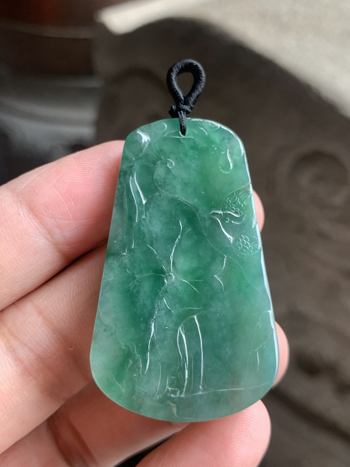 【喜上眉梢】方牌吊坠，裸石49.5*29*6 整体种色相融像把一汪春日的湖水凝进了玉里，水头足到光线下都透着清润的柔光，绿调温柔不艳俗，越看越有江南烟雨的清雅韵味。
牌面的雕工更是点睛之笔：舒展的荷叶脉络清晰，一只喜鹊停落其间，线条柔而不飘，把“荷（和）花+喜鹊（喜）”的吉祥寓意藏得含蓄又讨喜。没有繁复的堆砌，只靠流畅的雕工把“和和美美、喜事临门”的祝福揉进了玉的肌理里，日常戴不张扬，却处处透着温润贵气，无论是做日常吊坠，还是搭配中式穿搭，都能衬得人气质温婉又雅致。 不足之处在于侧边有一处表皮凹陷，无碍