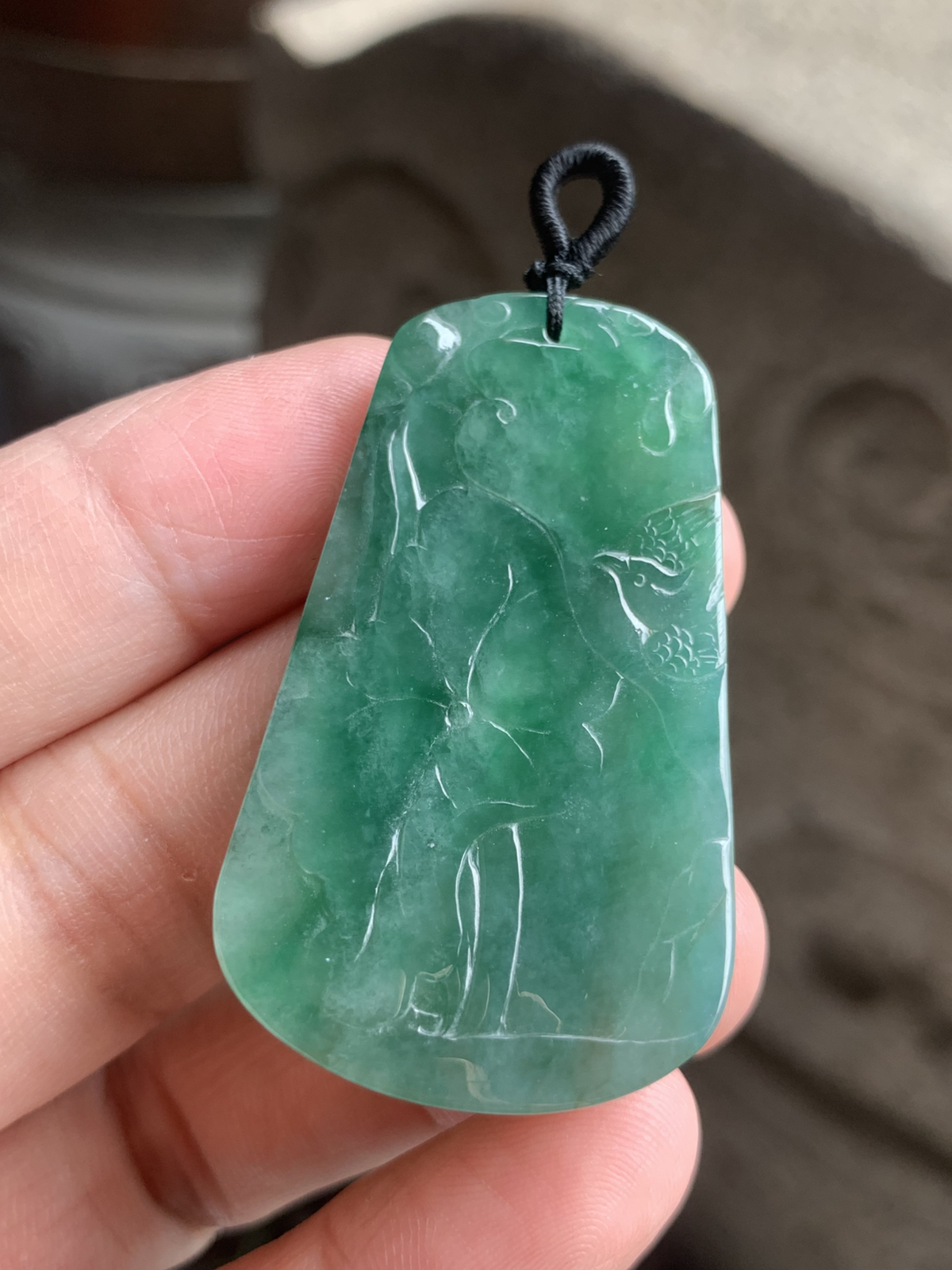 【喜上眉梢】方牌吊坠，裸石49.5*29*6 整体种色相融像把一汪春日的湖水凝进了玉里，水头足到光线下都透着清润的柔光，绿调温柔不艳俗，越看越有江南烟雨的清雅韵味。
牌面的雕工更是点睛之笔：舒展的荷叶脉络清晰，一只喜鹊停落其间，线条柔而不飘，把“荷（和）花+喜鹊（喜）”的吉祥寓意藏得含蓄又讨喜。没有繁复的堆砌，只靠流畅的雕工把“和和美美、喜事临门”的祝福揉进了玉的肌理里，日常戴不张扬，却处处透着温润贵气，无论是做日常吊坠，还是搭配中式穿搭，都能衬得人气质温婉又雅致。 不足之处在于侧边有一处表皮凹陷，无碍