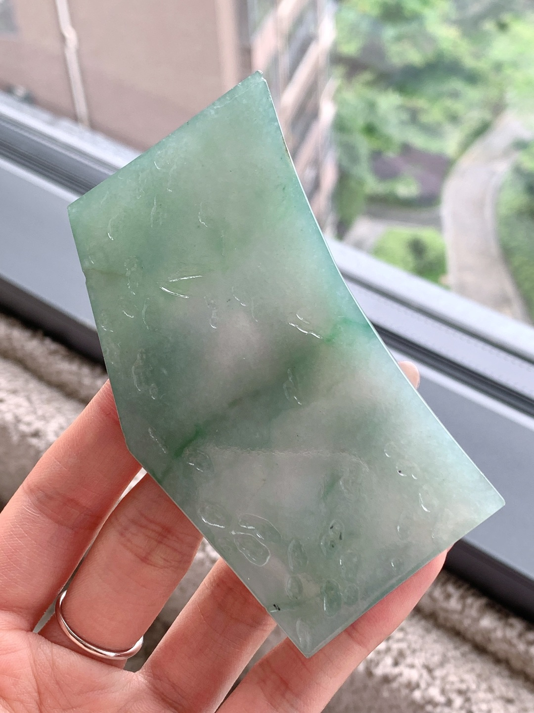 🫧 冰飘花/牌子料/片料/板料/特色料 可做牌子、人物、山水、动物、花件……等推荐参考 89-55.7-7.7 93.1克 材料优选 冰底凝清翠，飘绿映春山。 这方冰种飘绿翡翠片料，如凝住了一汪初春的山涧水，清润通透的冰底上，几缕翠色如烟似雾般晕染开来，自带朦胧柔美的江南气韵。它种老肉细、水头充盈，经玉雕师巧手雕琢，可化为一幅清雅的山水牌，将这份春日生机定格其间，寓意母亲如青山般安稳，如绿水般温柔，庇佑她岁岁无忧、心境澄明；也可化作一枚平安无事牌，以素面呈现这份天然之美，象征着岁月静好，愿她余生皆安，喜乐常伴。