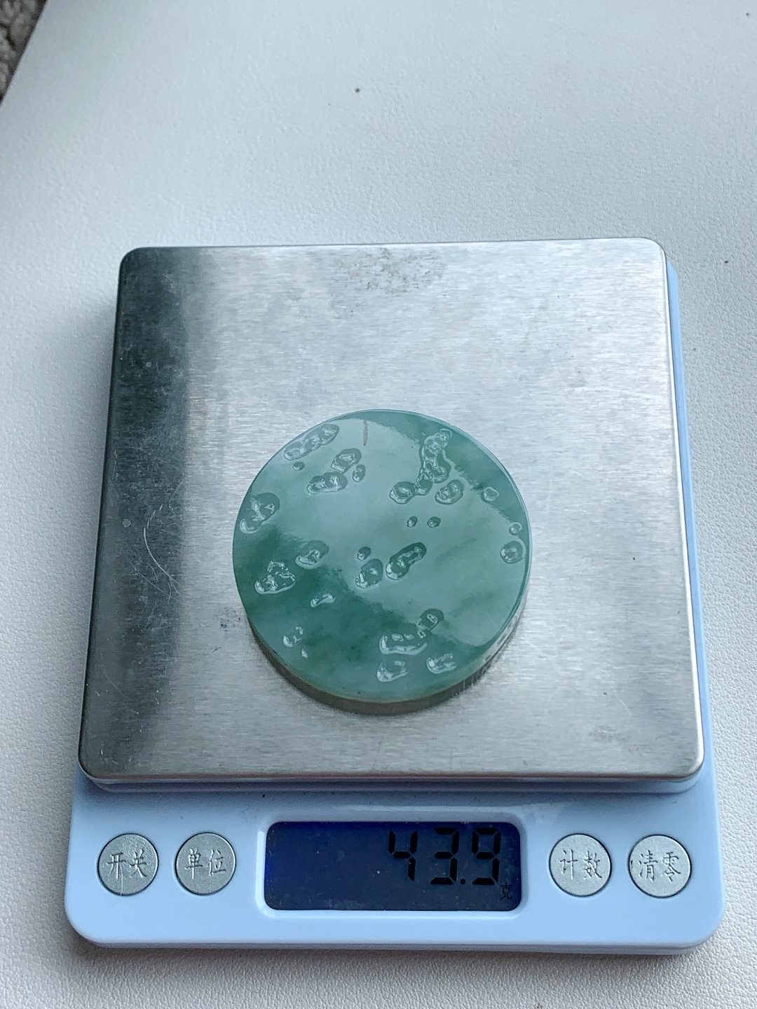 【材料】🫧 冰飘花/牌子料/镯心料/特色料 【题材】可做牌子、人物、山水、动物、花件……等推荐参考 【尺寸】48.4-7.3 【重量】43.9克 材料优选 · 云栖晴水凝清碧，风染浮花映玉圆。 ·冰糯种飘花翡翠圆牌料，质地莹润胶感透亮，晴水底色清透如溪，飘花如流云漫卷、似远山含黛，晕染出雨后初晴的空灵意境，可雕刻无事圆牌、山水牌或云纹题材，寓意圆满顺遂、清雅安然，佩戴间尽显温润内敛的东方气韵。