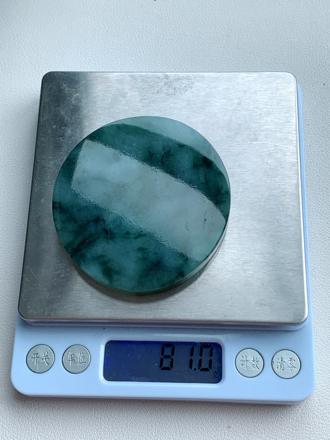 【材料】🫧 冰飘花/牌子料/镯心料/特色料【题材】可做牌子、人物、山水、动物、花件……等推荐参考【尺寸】65-60.4-7.1【重量】81克材料优选· 翠染烟岚凝碧色，云栖圆玉映清光。·冰糯种飘花翡翠圆牌料，质地莹润胶感透亮，浓绿飘花如远山含黛、似云海翻涌，晕染出水墨山水画般的写意意境，可雕刻山水无事牌、怀古圆牌或云纹题材，寓意山河无恙、圆满顺遂，佩戴间尽显温润内敛的东方气韵。