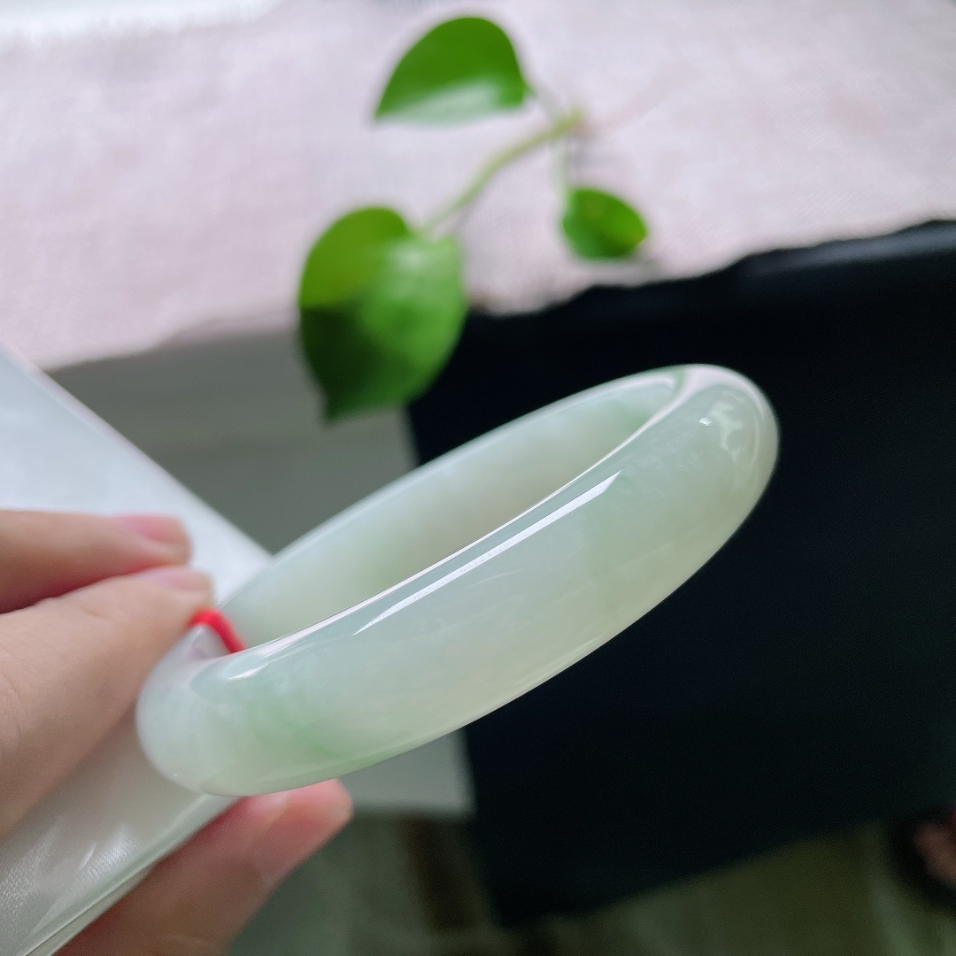 56.8/12.4/9.1，飘花正圈，横裂，底色莹白温润，几缕淡翠如烟似雾般晕染在玉身两侧，清浅灵动。ss55795a