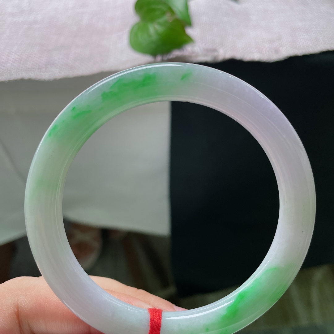 58.6/8.7，春彩圆条，横裂，基底是柔和温润的淡紫色，镯身两侧散落着几抹鲜亮的翠绿色飘色，色彩相