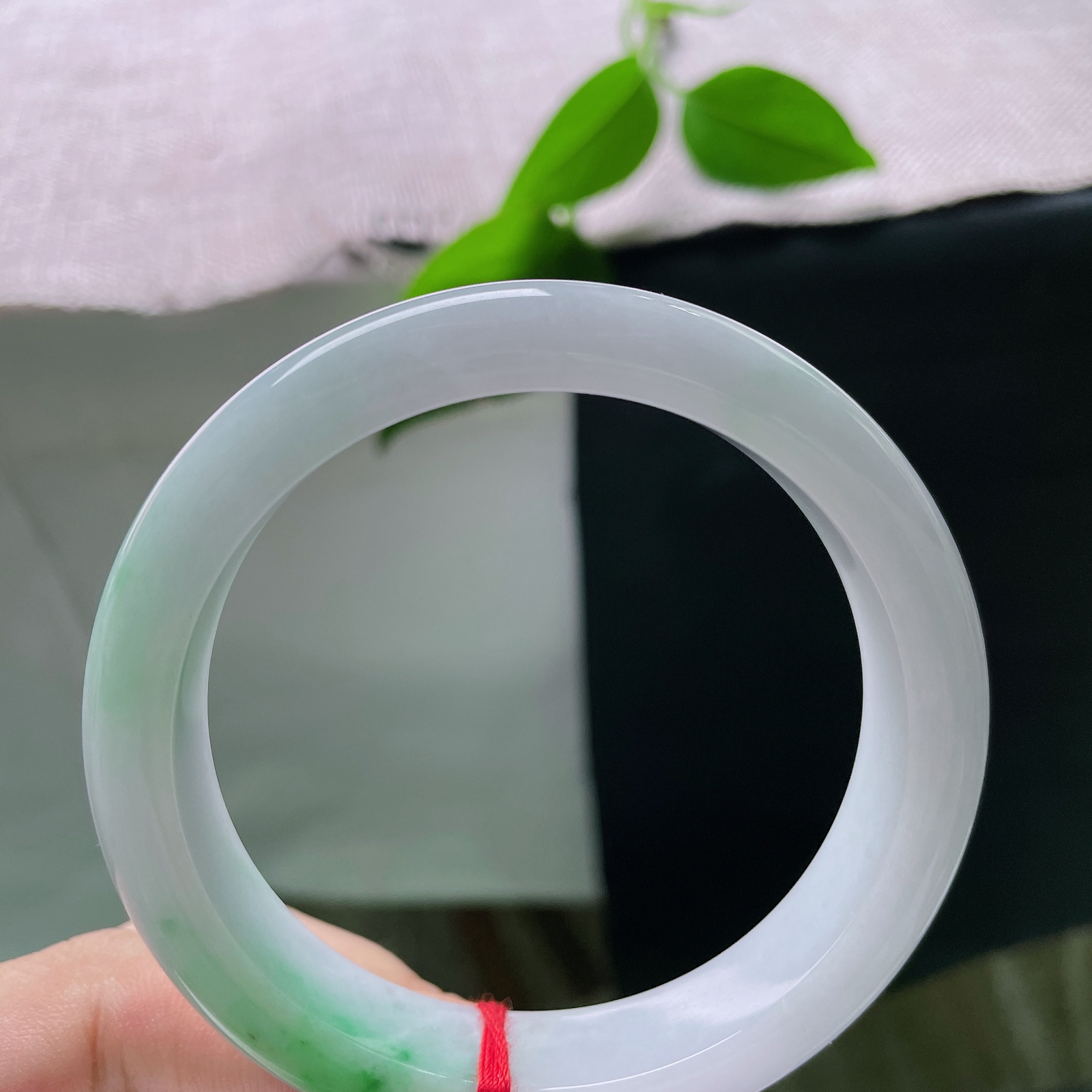 58.5/12.6/8.8，白底青正圈，棉线，玉底温润细腻，一截鲜活翠色自镯底缓缓晕染铺开，浓艳自然，似春日新芽落于素玉之上，ss56457a