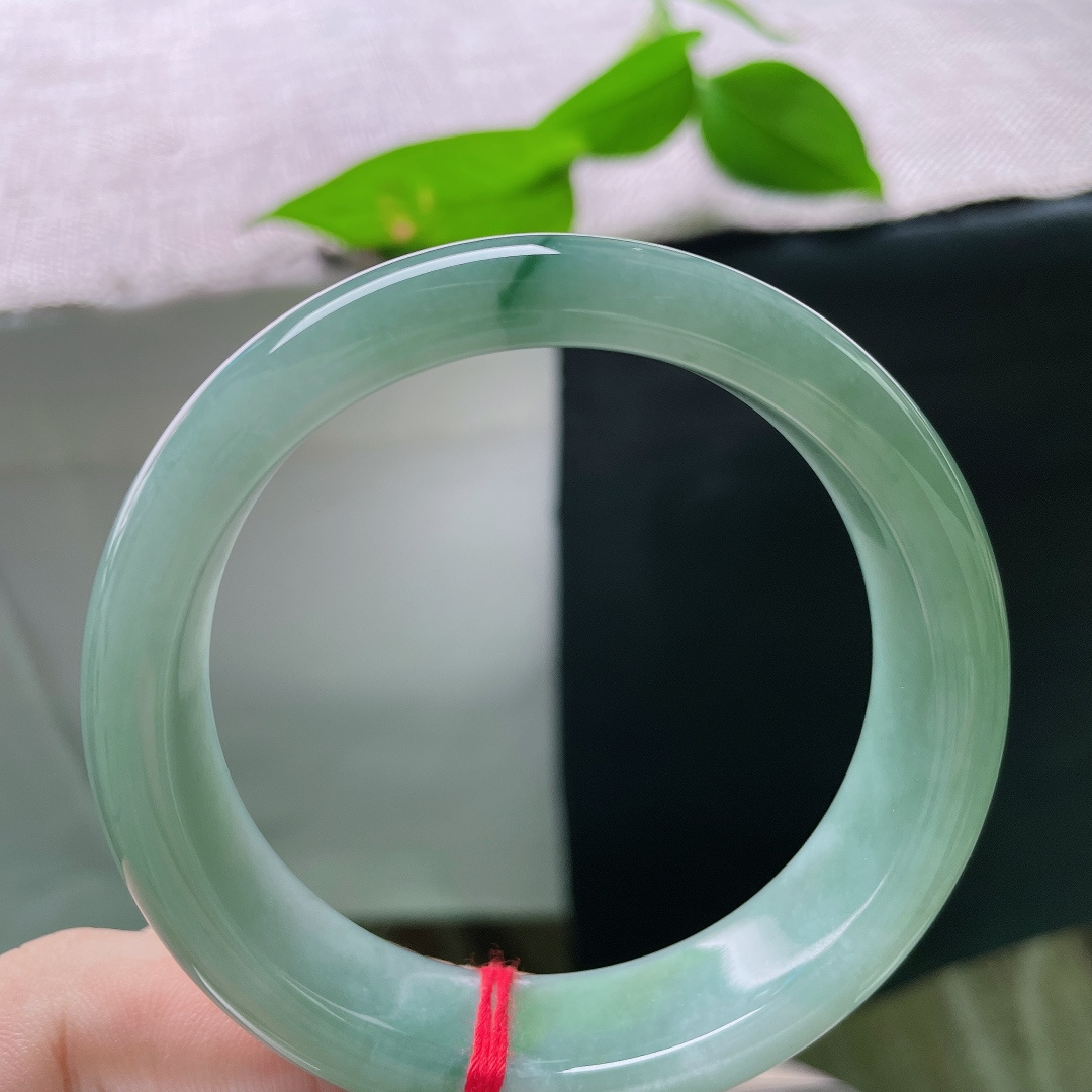 飘花正圈，无裂，一镯浸青水，微光藏玉间。沉静油青底色温润内敛，细缕翠色轻缀镯身，腕间自带低调雅致的韵