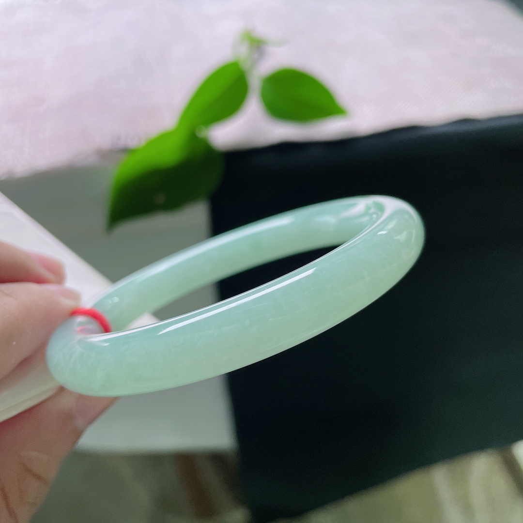 果绿圆条，有棉线，一镯凝露水，清翠润腕间。匀净浅绿温润通透，素面无华，以天然玉色勾勒简约中式温柔，沉静耐看，清雅动人。ss55981a