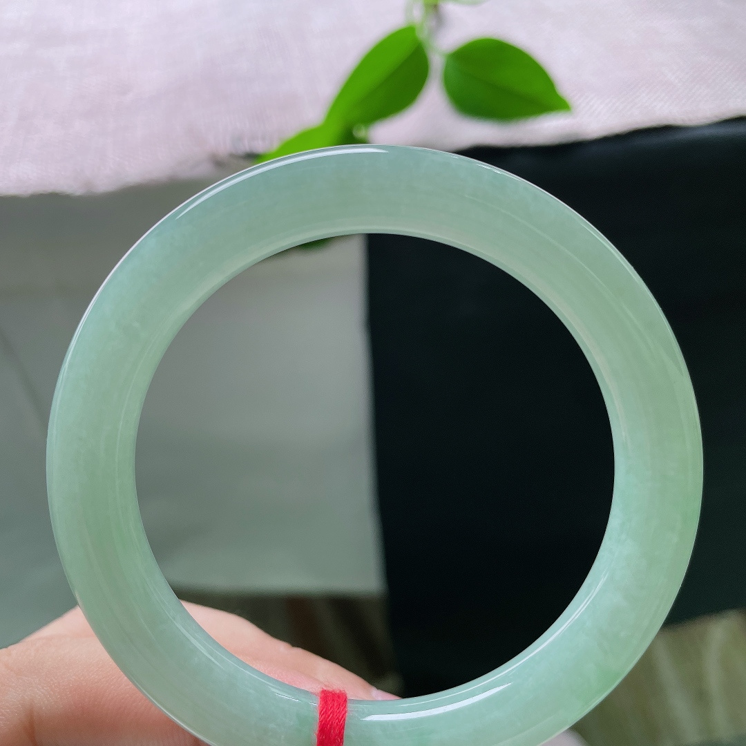 果绿圆条，有棉线，一镯凝露水，清翠润腕间。匀净浅绿温润通透，素面无华，以天然玉色勾勒简约中式温柔，沉静耐看，清雅动人。ss55981a