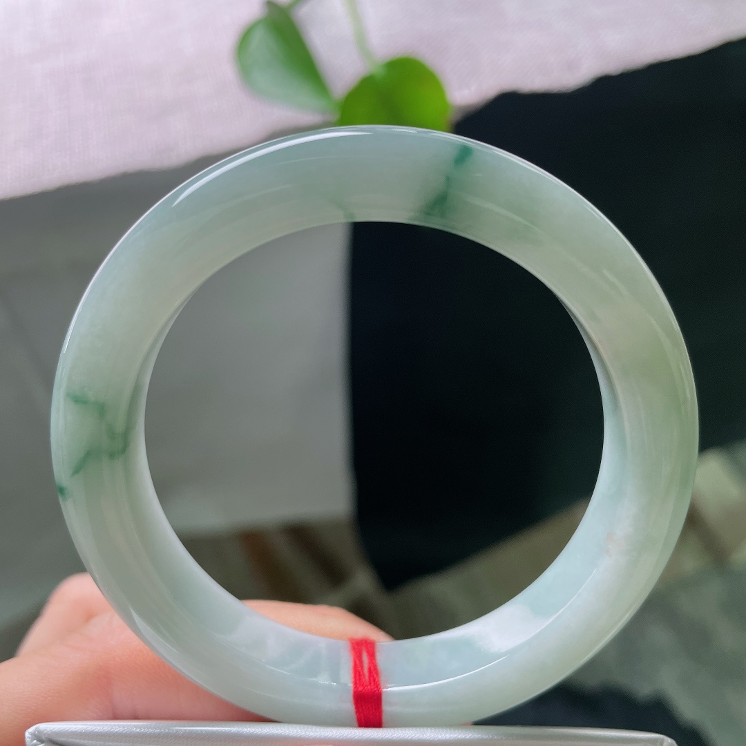 55.2/10.8/9.3，飘花正圈，皮纹，细腻水润，几缕墨蓝花丝随性流淌于镯身，如同水墨在玉底缓缓晕开，自带写意山水意境，清冷又雅致。ss56915a