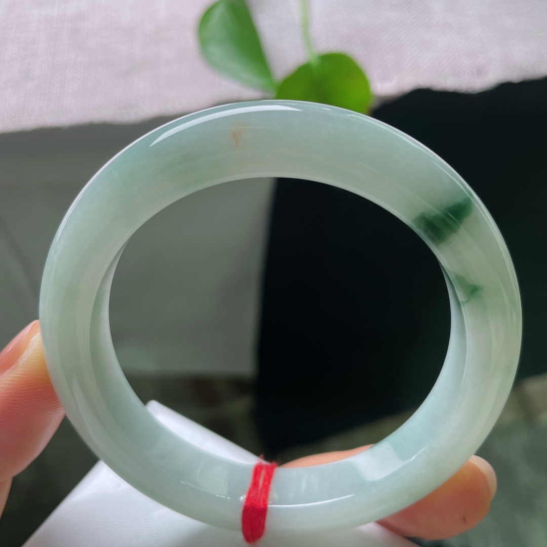 55.2/10.8/9.3，飘花正圈，皮纹，细腻水润，几缕墨蓝花丝随性流淌于镯身，如同水墨在玉底缓缓晕开，自带写意山水意境，清冷又雅致。ss56915a