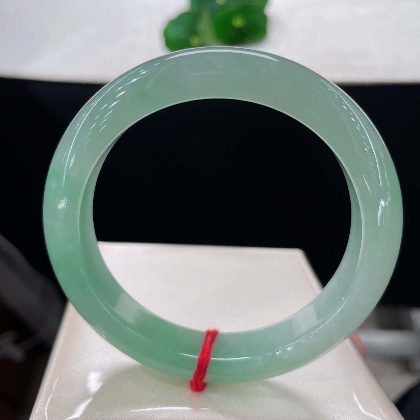圈口56.3/11.8/8.6，果绿正圈，56/57可戴，仿若平湖浸柳，质地澄澈莹润。通体匀润淡绿。无裂。