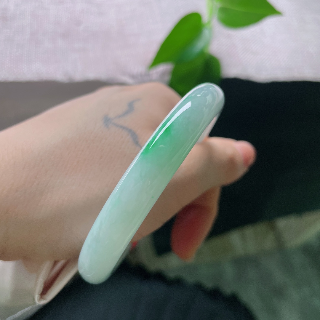53.1/10，飘绿圆条，一点皮纹，一抹鲜翠悄然落于镯身，翠色灵动鲜活，如春风拂过山间碧潭，清逸温婉。ss56713a